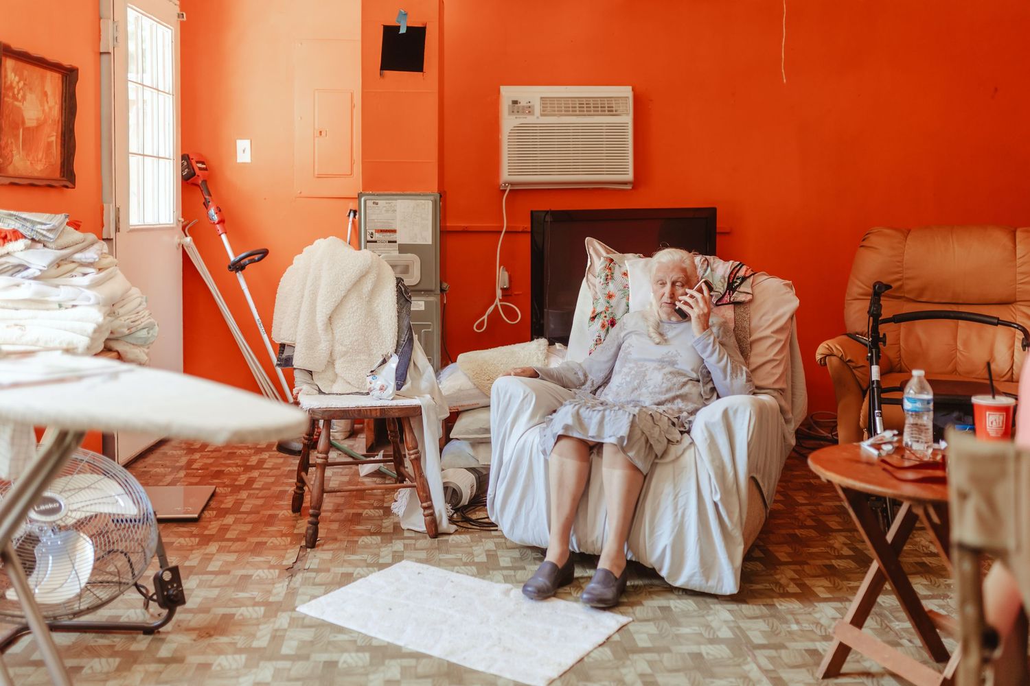 Room with vibrant orange walls and white covered chairs arranged in rows.