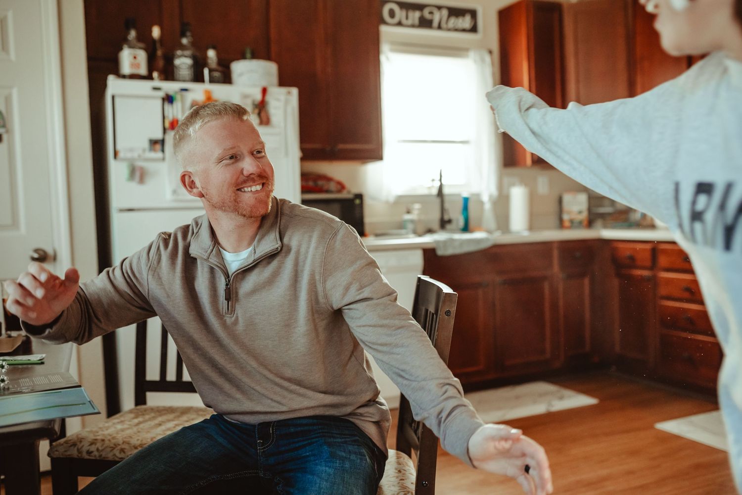 Casual conversation happening in a warm, sunlit kitchen.