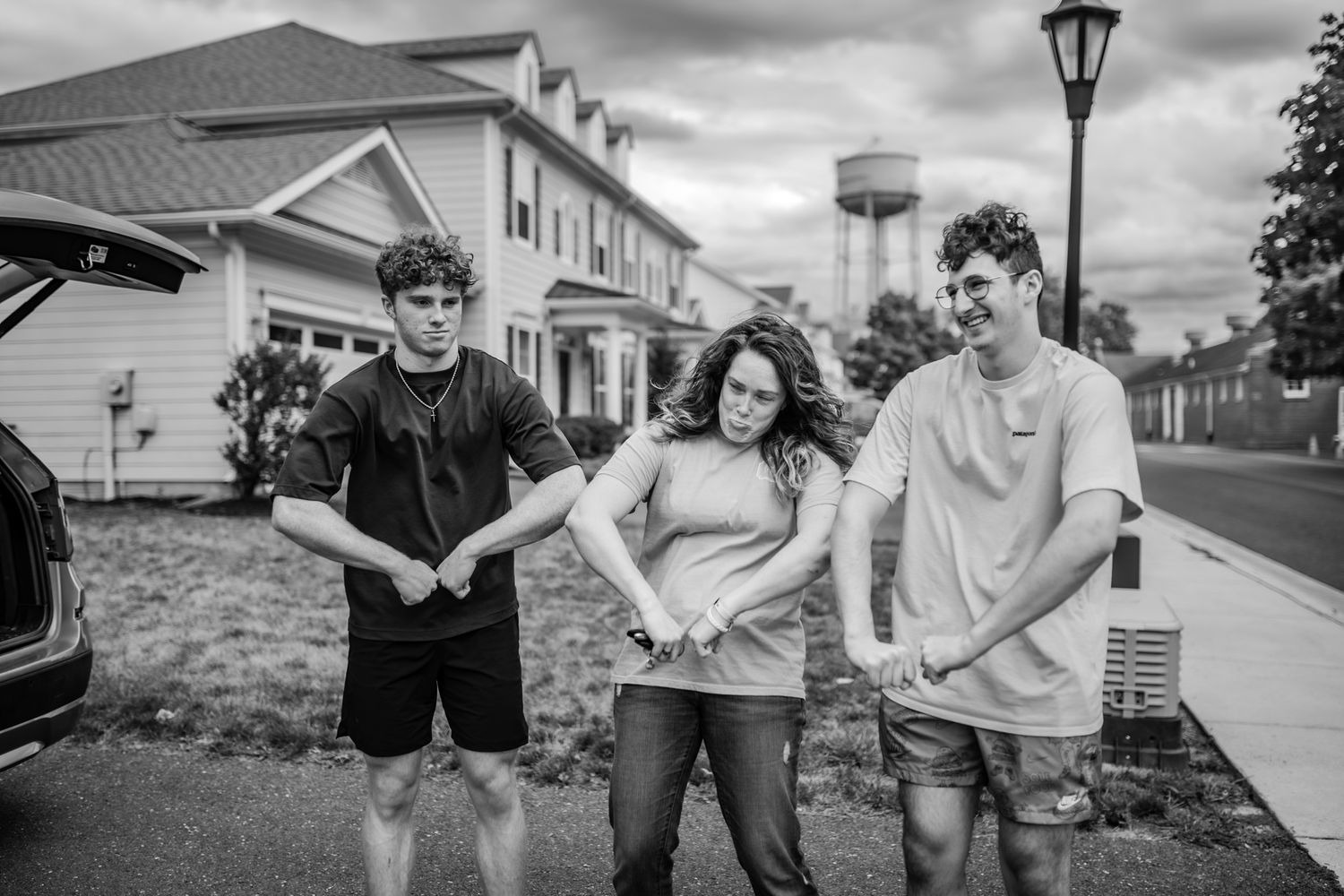 A casual group pose on a residential street with a water tower visible in the background.