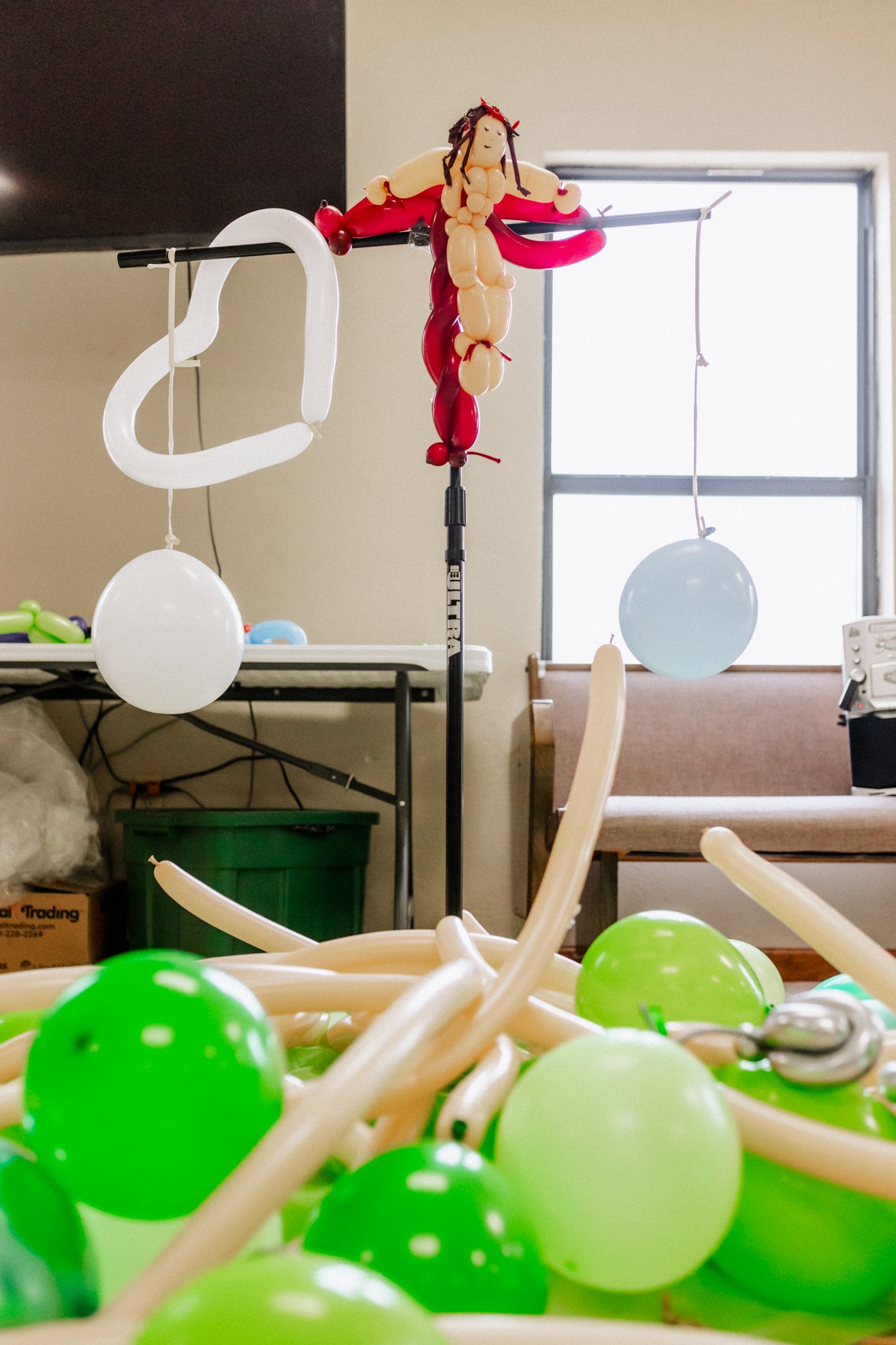 Green and white balloons arranged in a row against a light background in an indoor space.