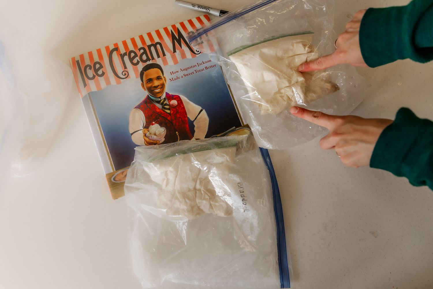 Chocolate and vanilla ice cream scoops being scooped from containers on a marble surface.