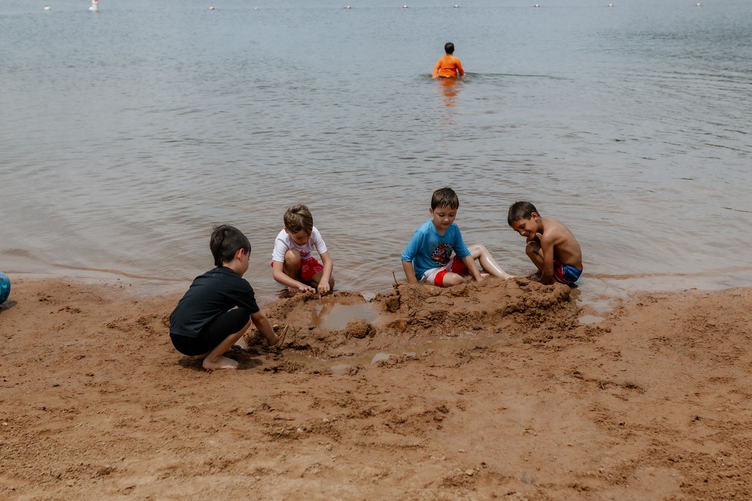 People playing and relaxing along a sandy beach shoreline.