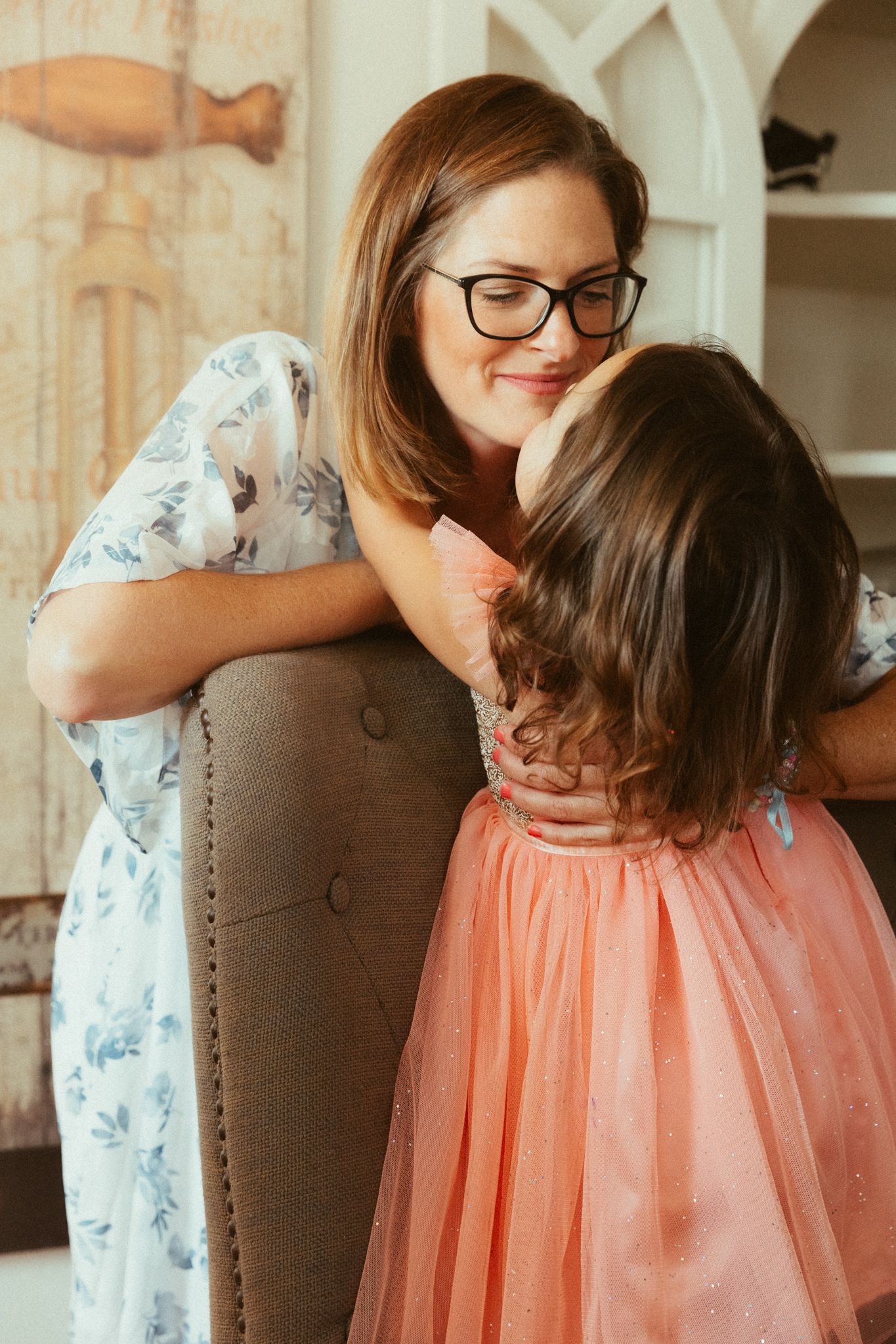 Tender moment captured in warm tones showing affectionate interaction in home with mom and daughter on her documented birthday.