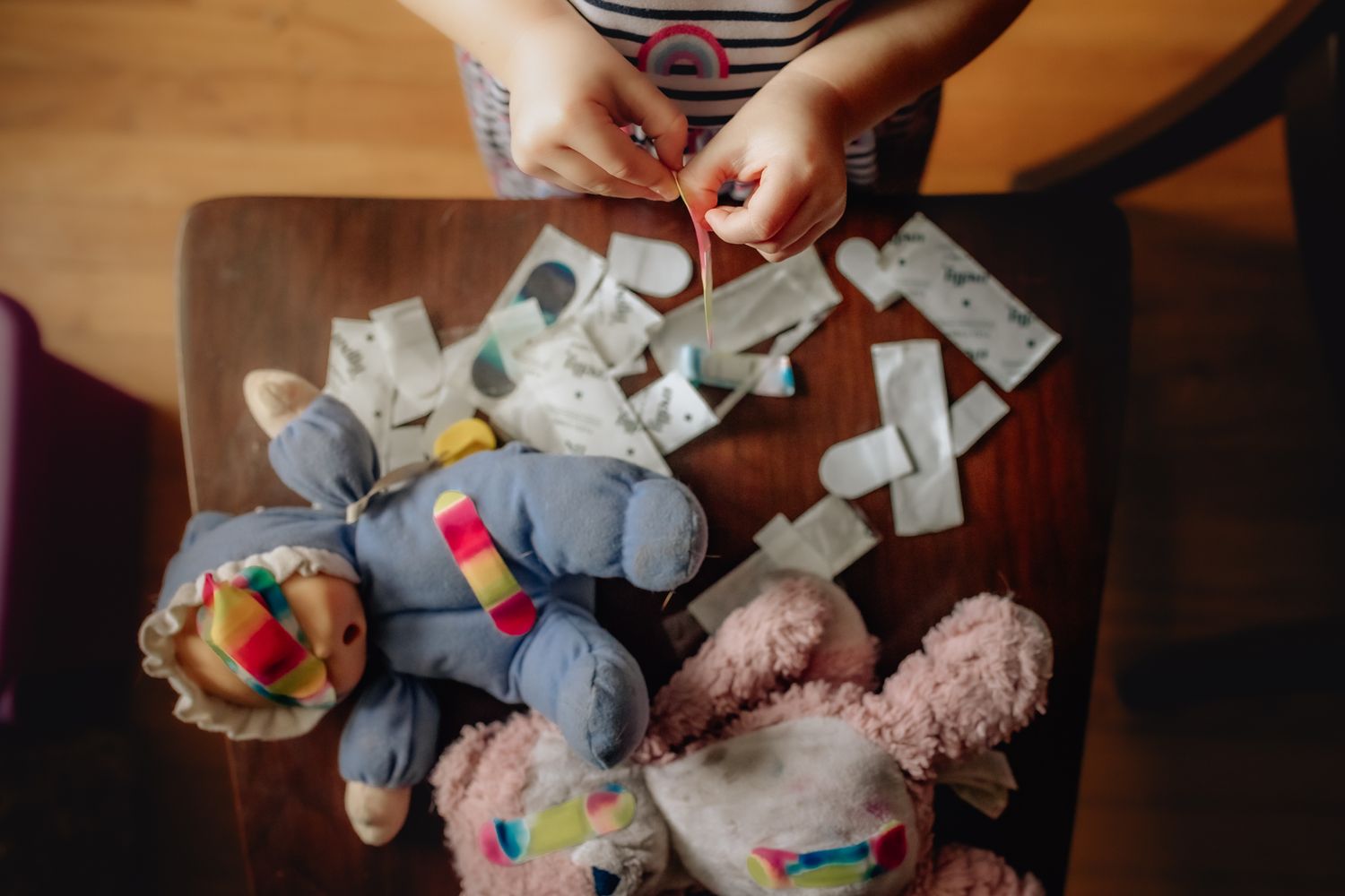 Grey stuffed animal toys scattered on a dark surface next to someone's hands.