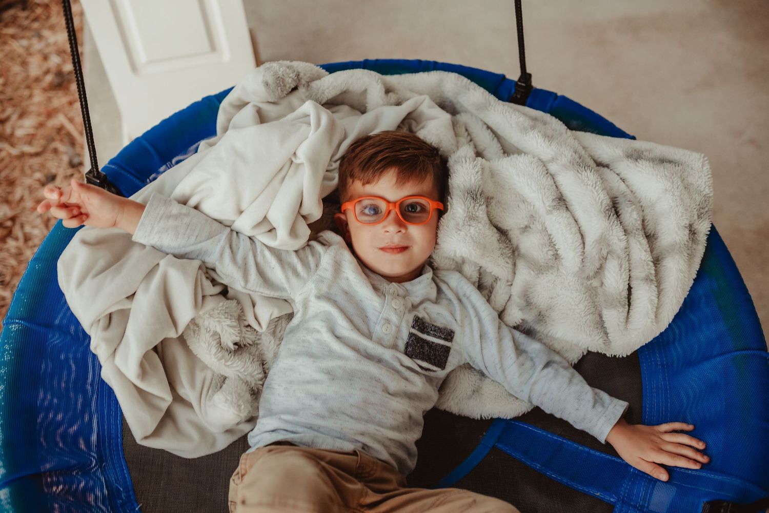 Child resting on blue bedding with white blankets in natural light.
