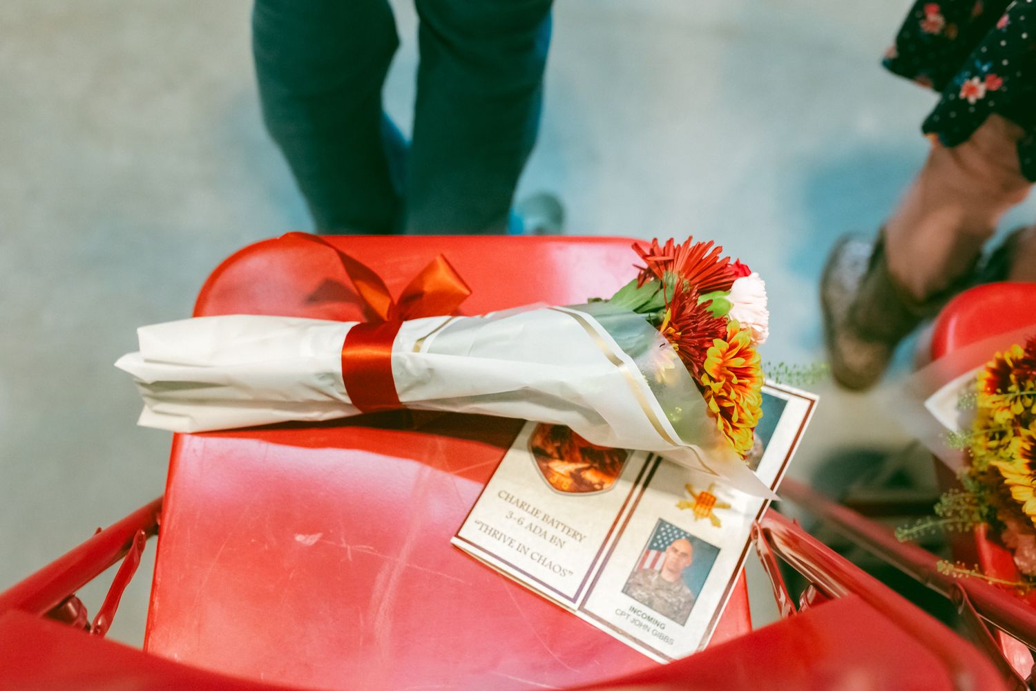 Hands arranging colorful flowers and gift boxes on a wooden surface for a festive celebration.