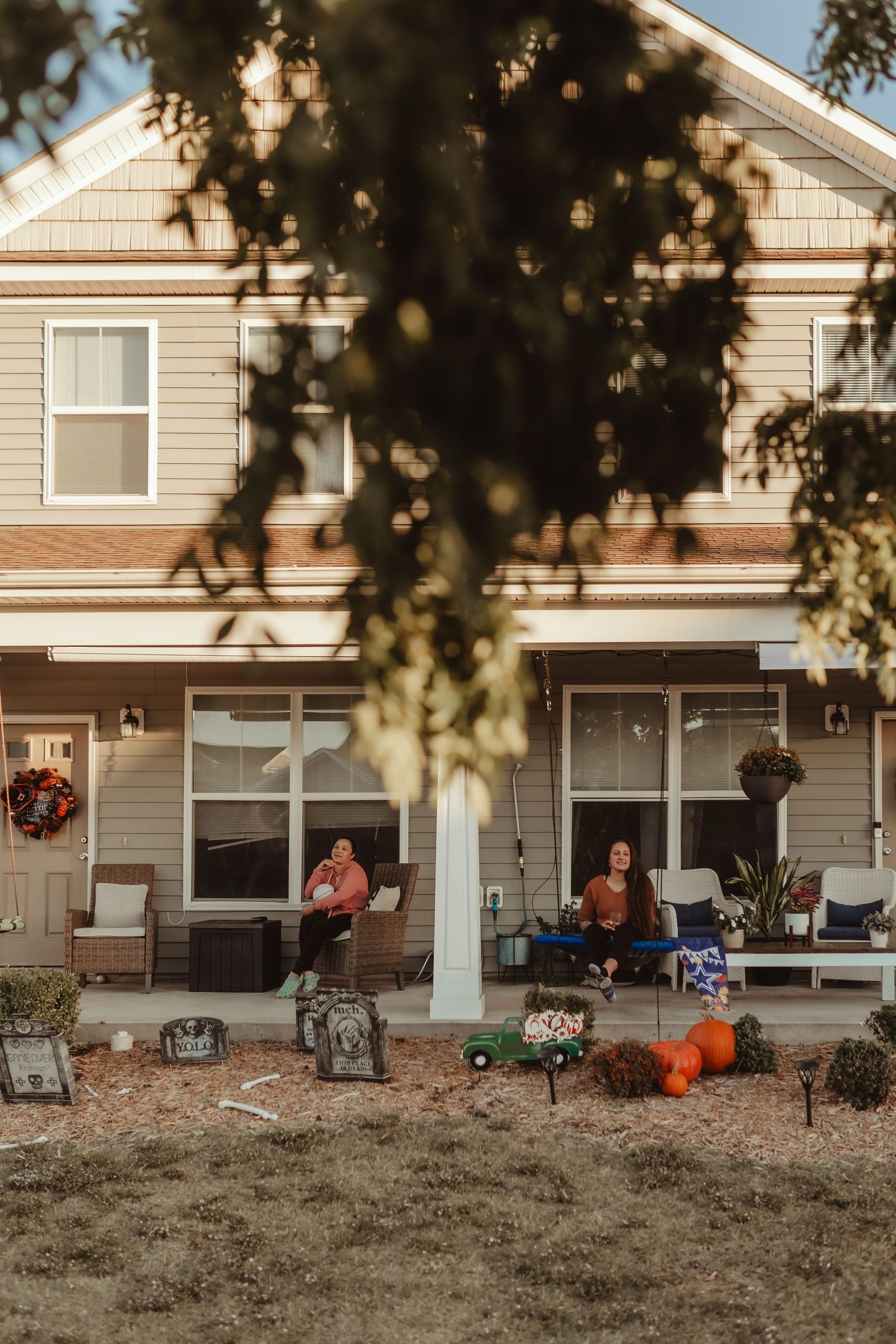 Halloween decorated front porch of a two-story house with autumn decorations.