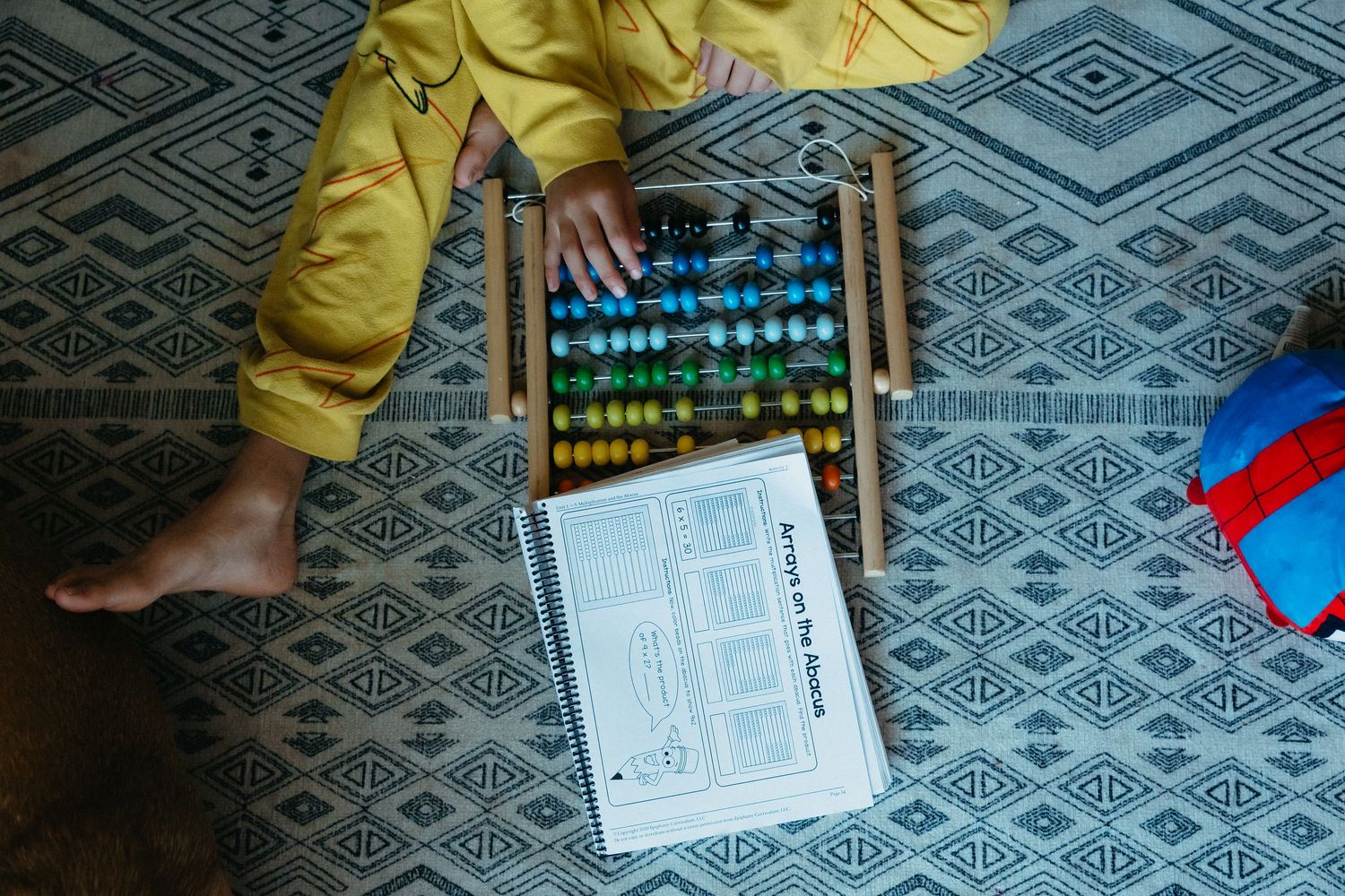 Someone adds colorful beads to a project on a geometric-patterned fabric surface.