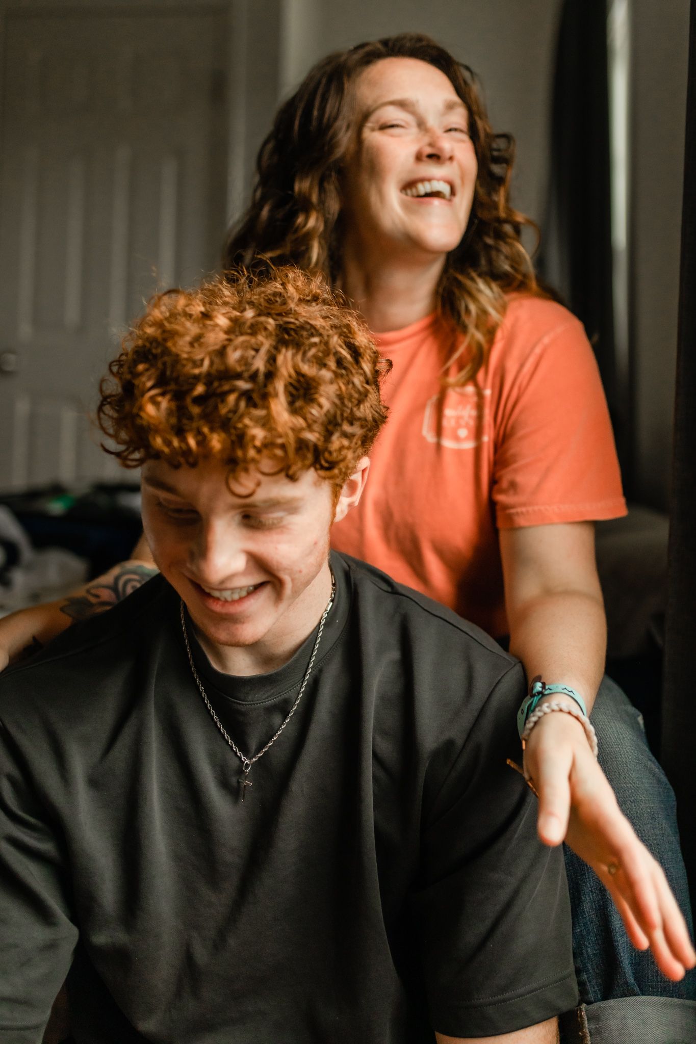 Candid moment showing genuine joy and laughter between two people in casual attire. In-Home Photography Liz Perez
