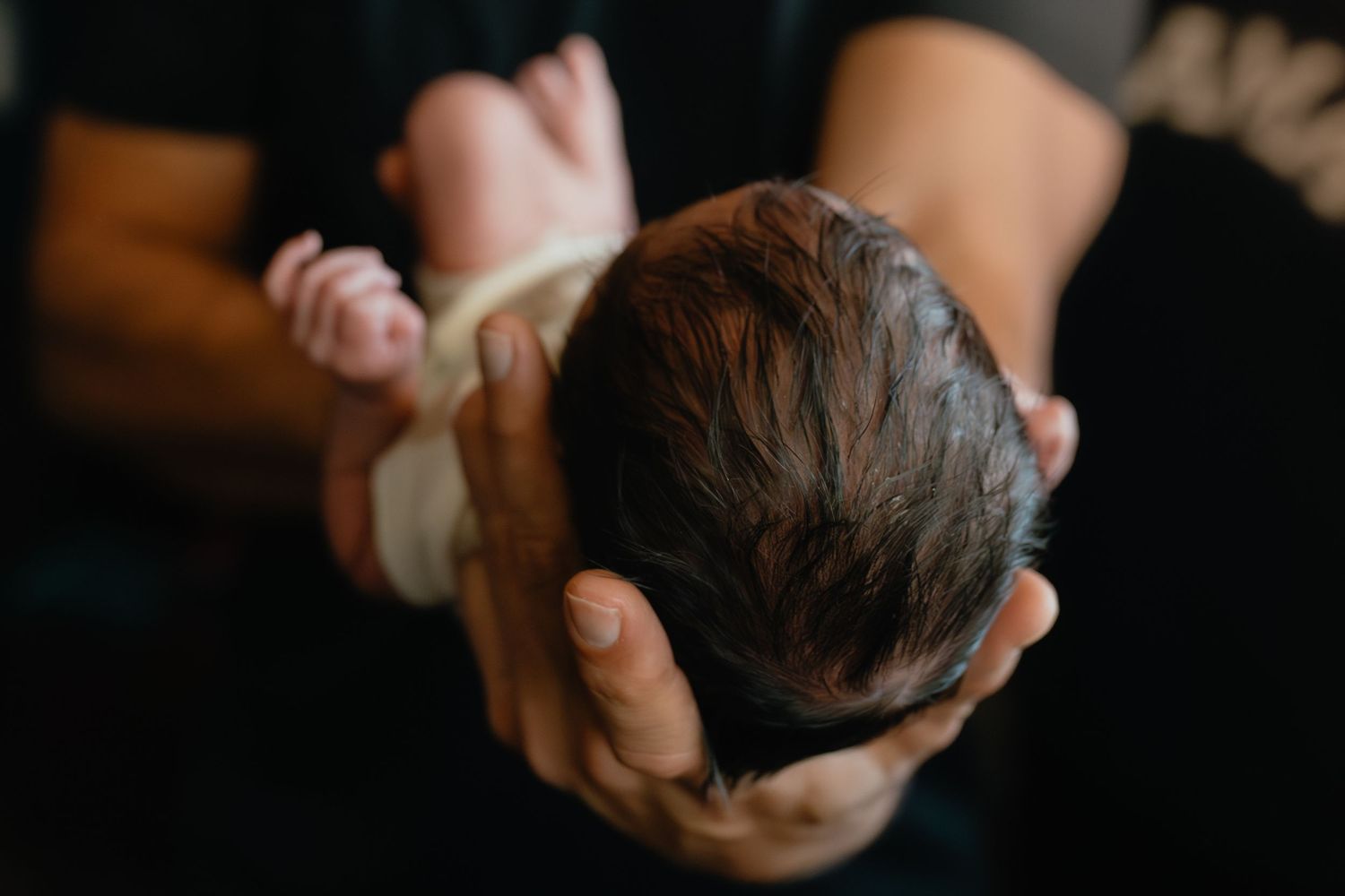 Intimate close-up photography of hands and gentle touches in dark lighting.