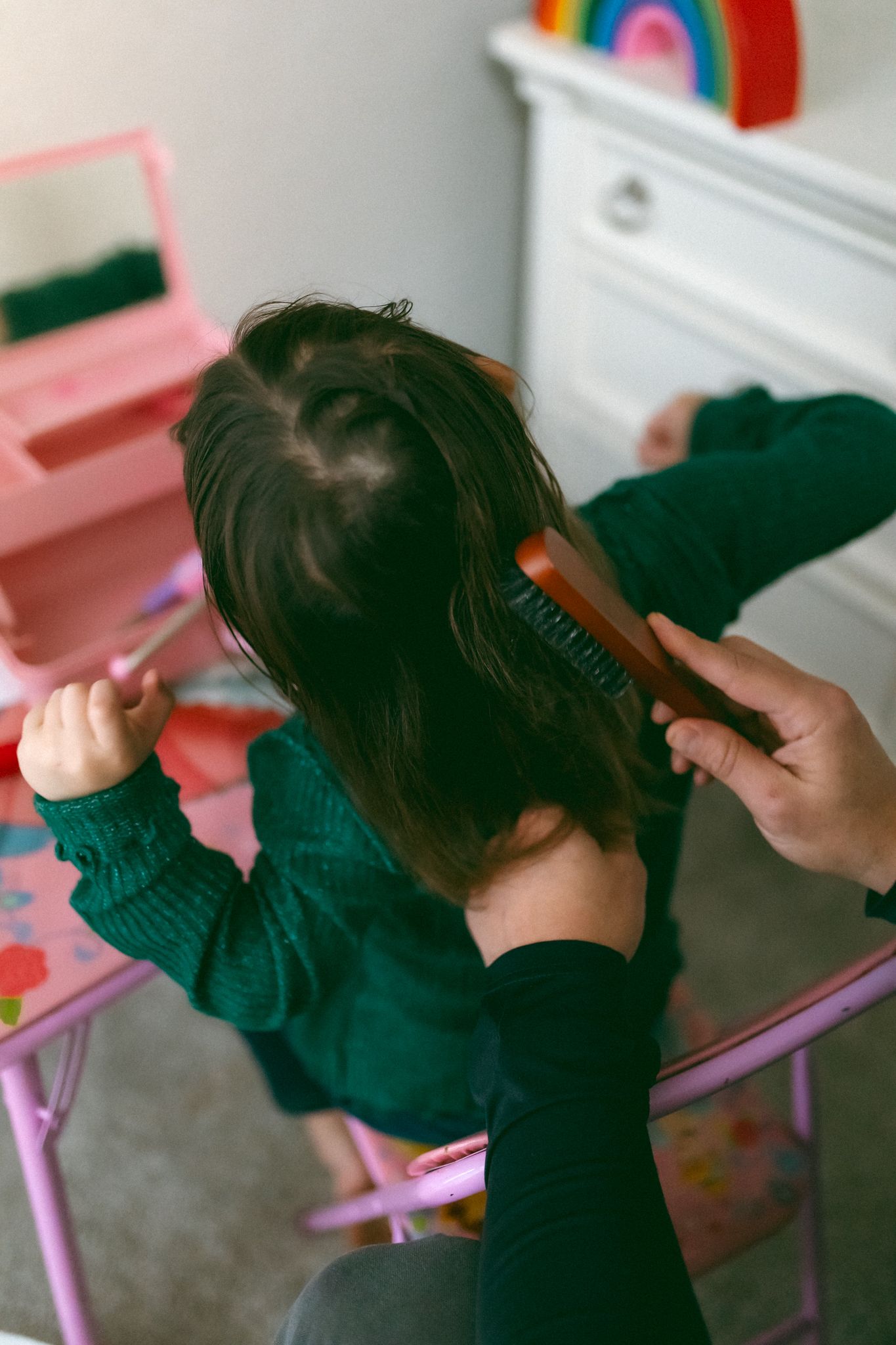 Hair styling session showing hands working with dark hair in an indoor setting.