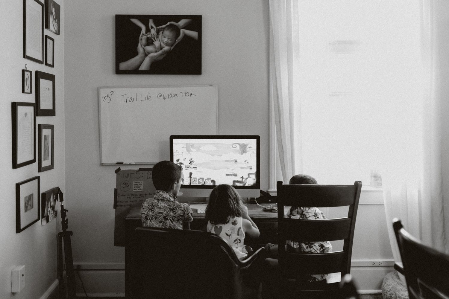 Home office setup with computer monitor and framed artwork on wall in black and white.