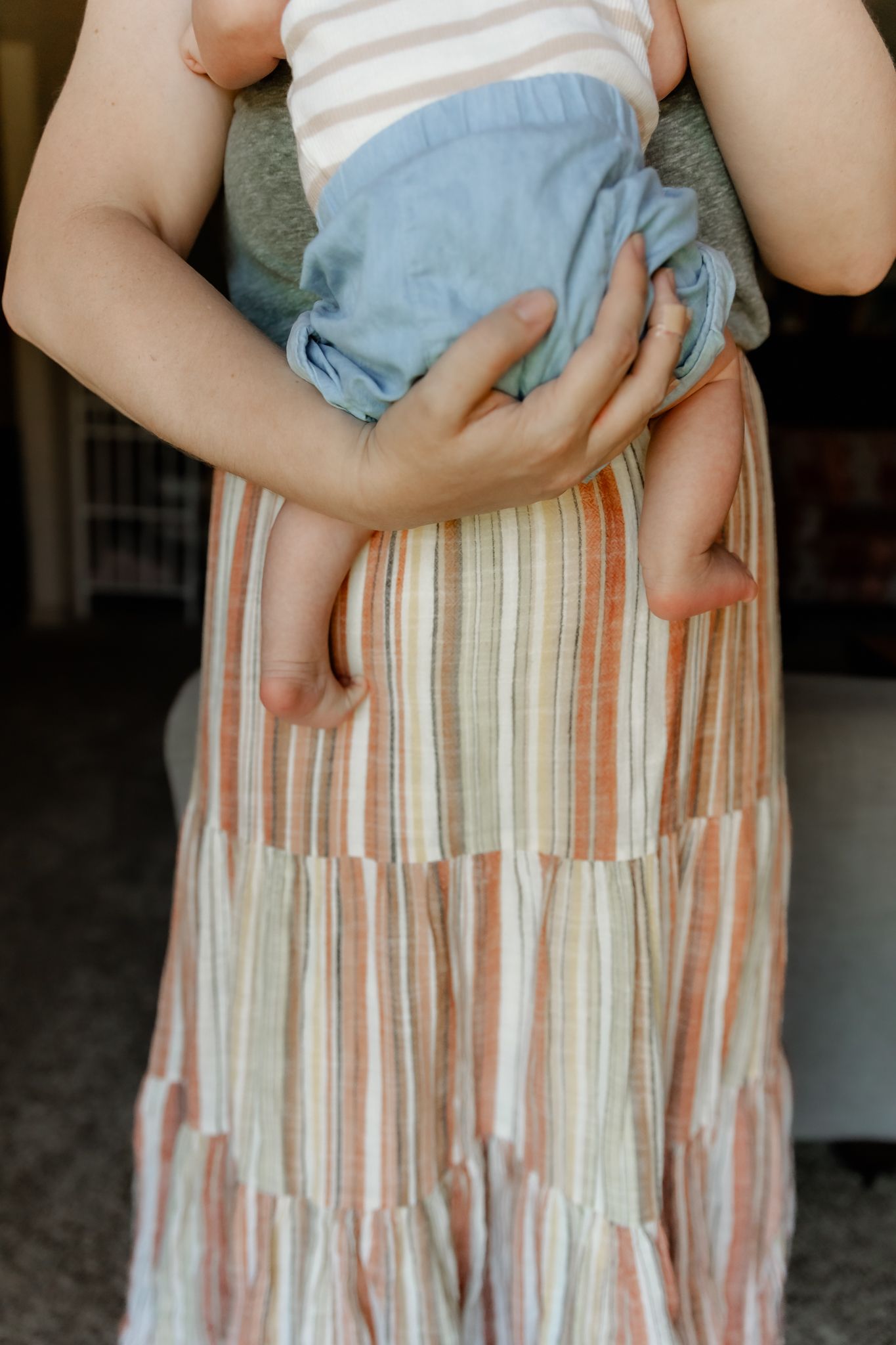 A series of progressive photos showing a person in a striped skirt holding a small baby from different angles.