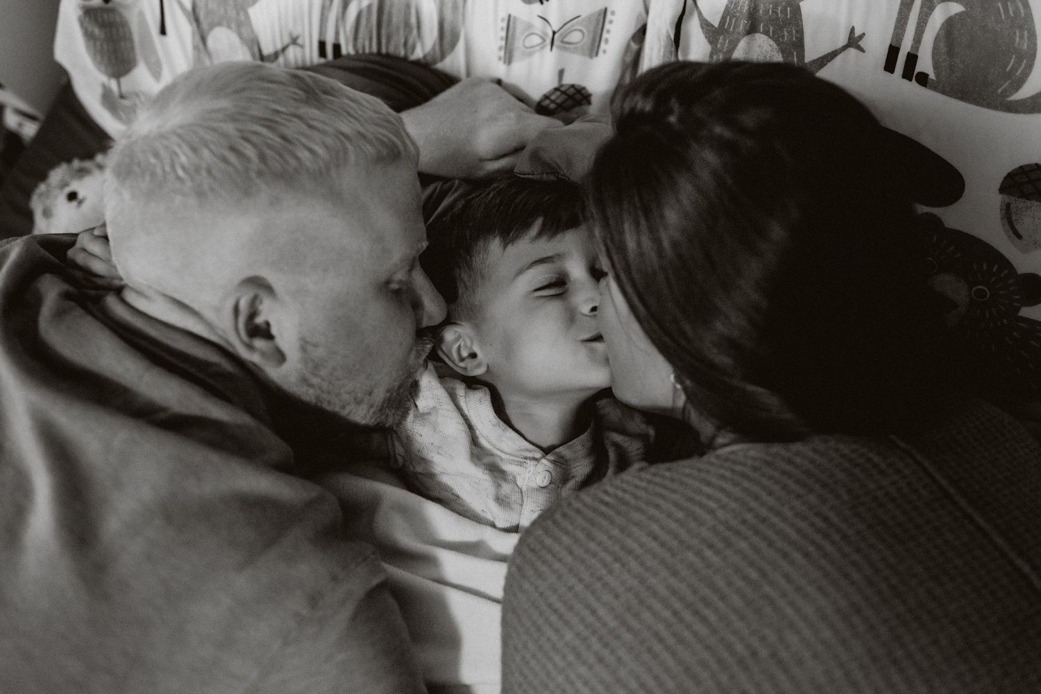 A tender moment of rest and connection between caregiver and child on white bedding.