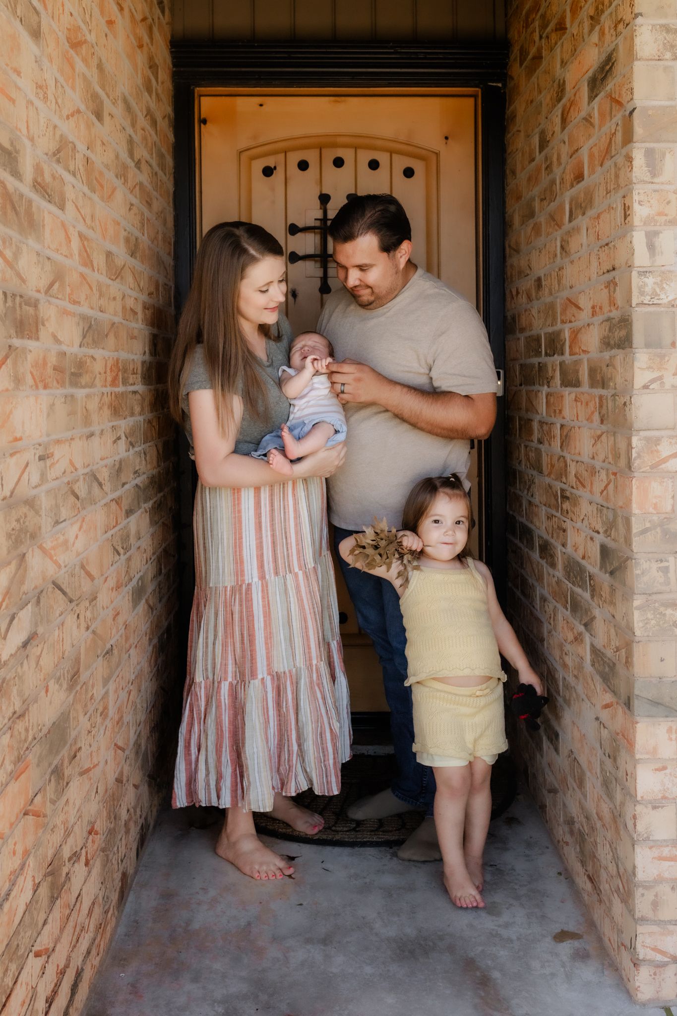 Family stands together in a brick entryway of their home.