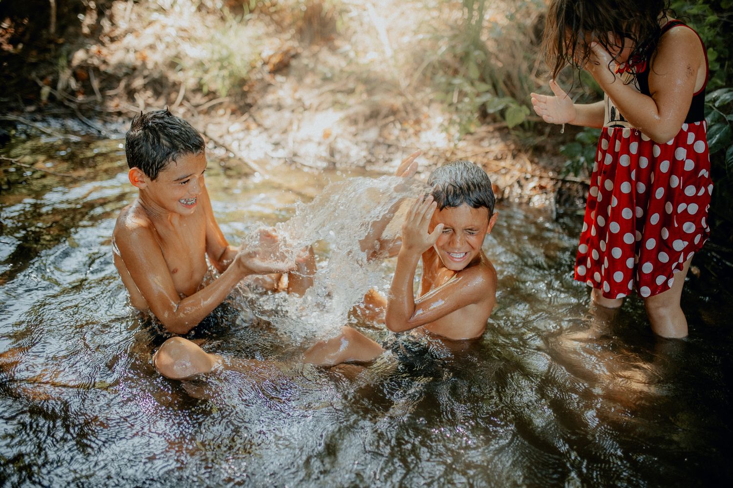 Children playing and splashing in shallow flowing water on a sunny summer day.