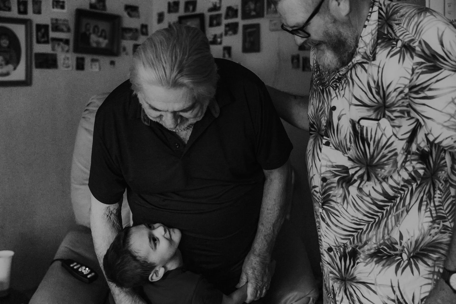 A tender black and white portrait in a room decorated with photographs.