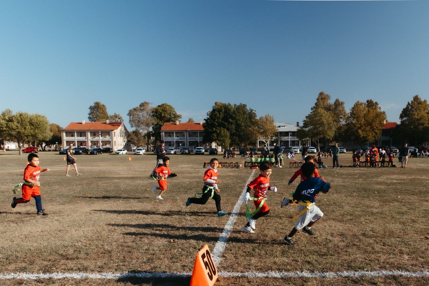 People playing a casual game of soccer on a dry grass field during a sunny day.