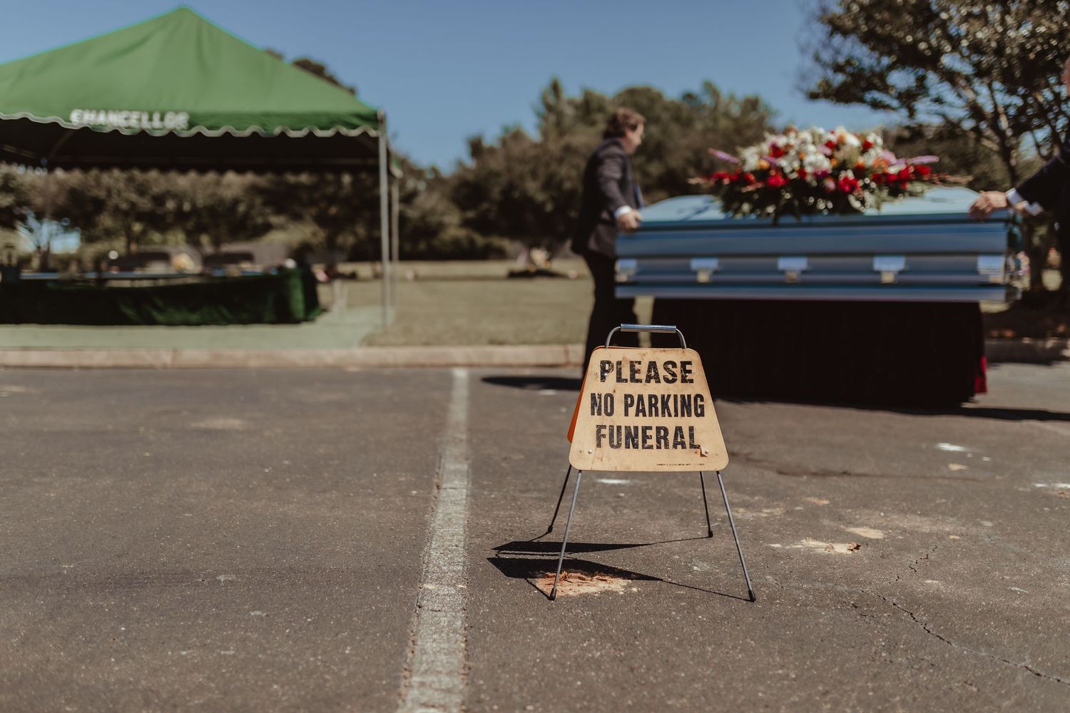Green canopy tent set up outdoors with signage for a gathering or event.