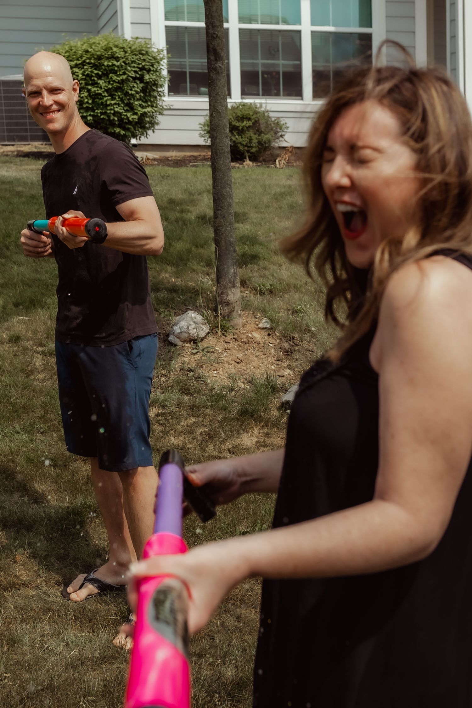 Playful water gun fight scene in a suburban backyard on a summer day.