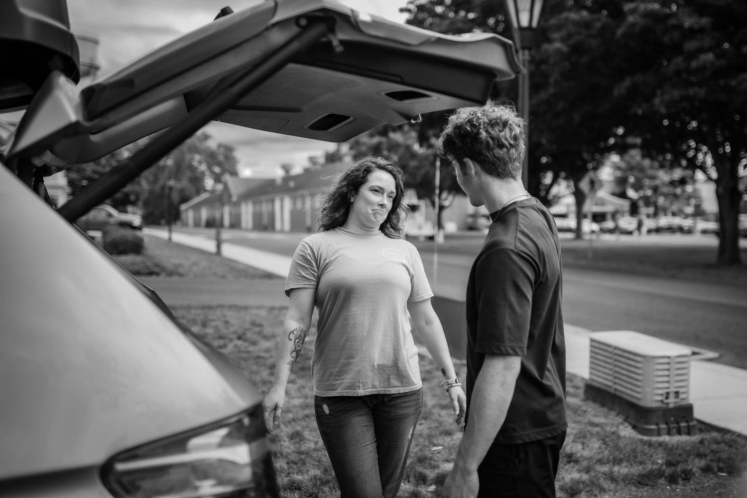 Group examining the exterior of a parked vehicle on a residential street.