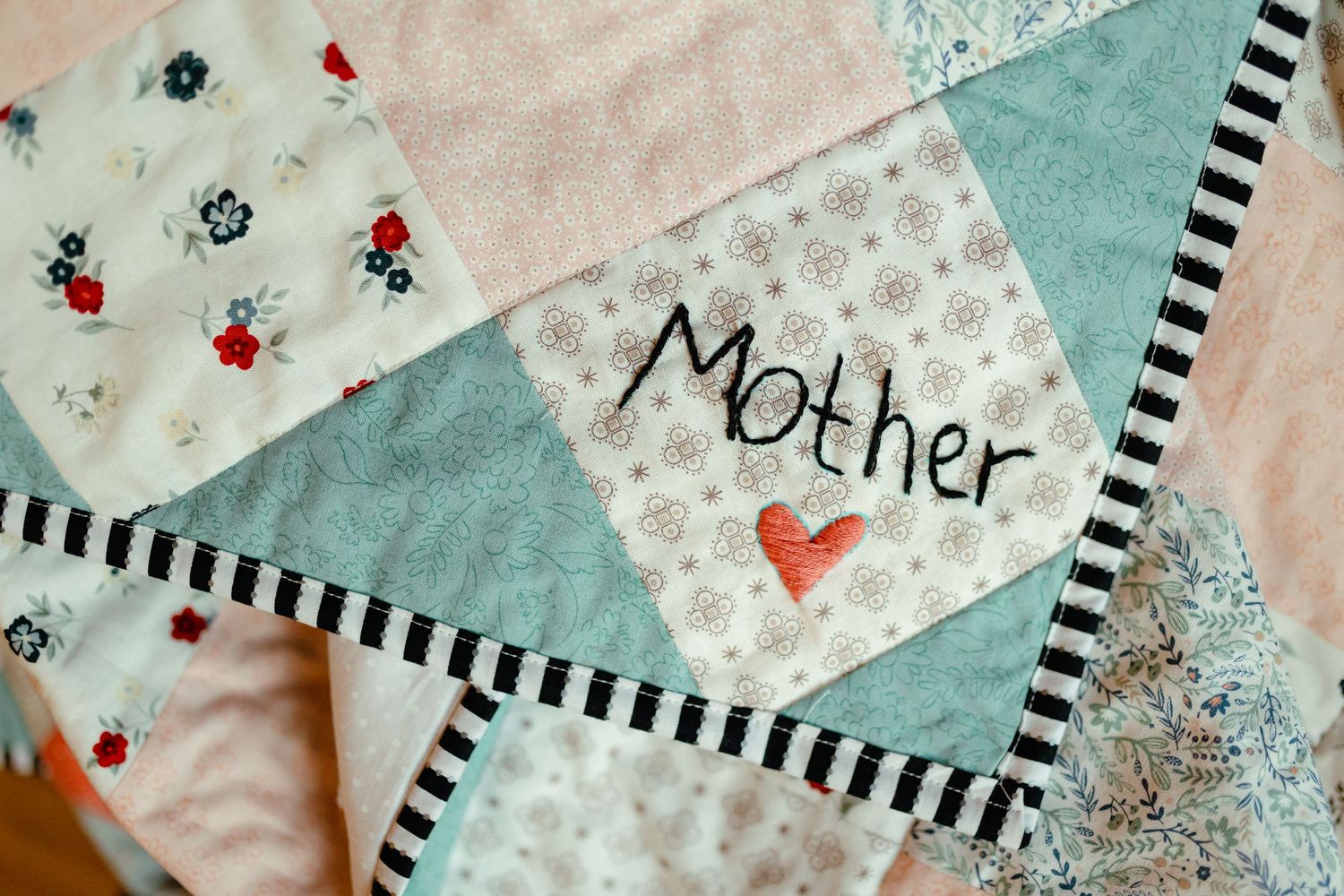 Close-up of a decorative quilt with blue and white patterns and red heart accents.