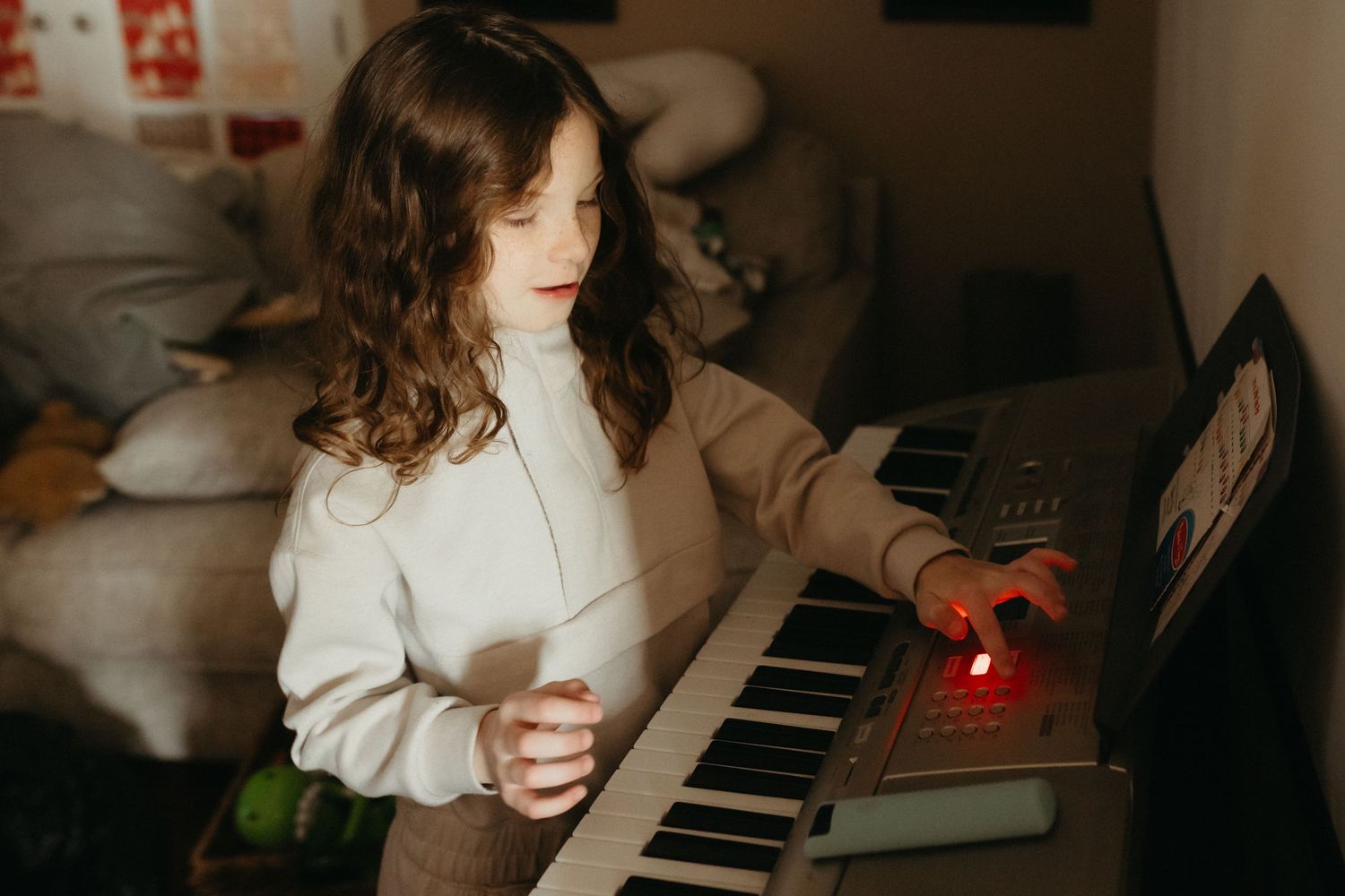 Someone playing a keyboard in a dimly lit room with soft lighting.