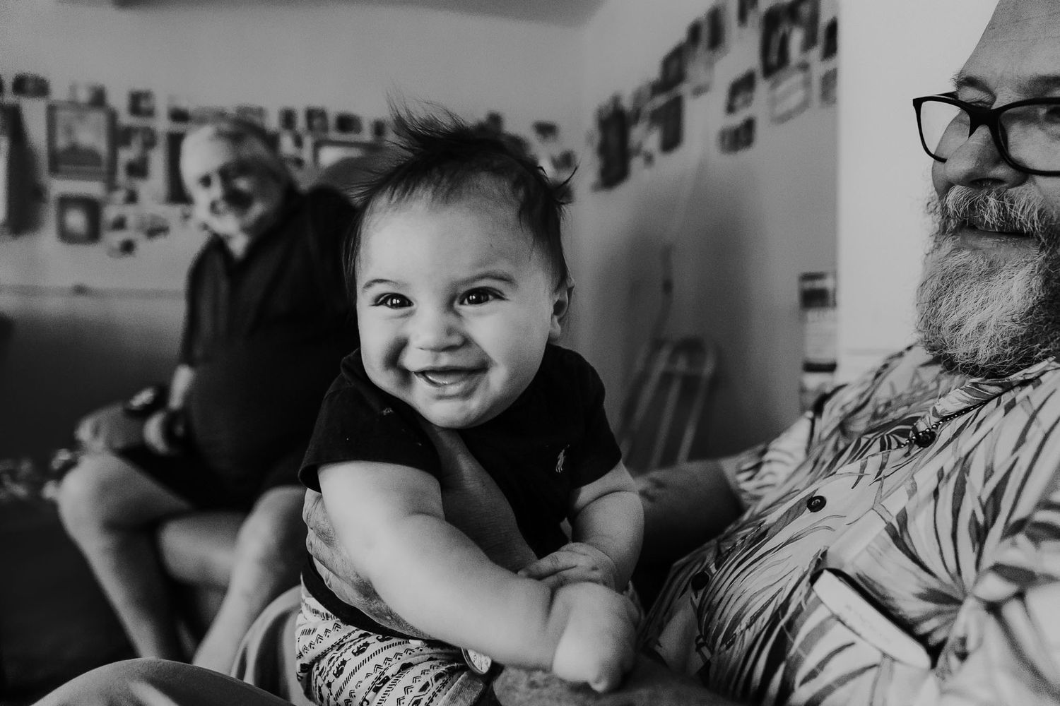 A joyful moment captured in black and white with photo-covered walls in the background.