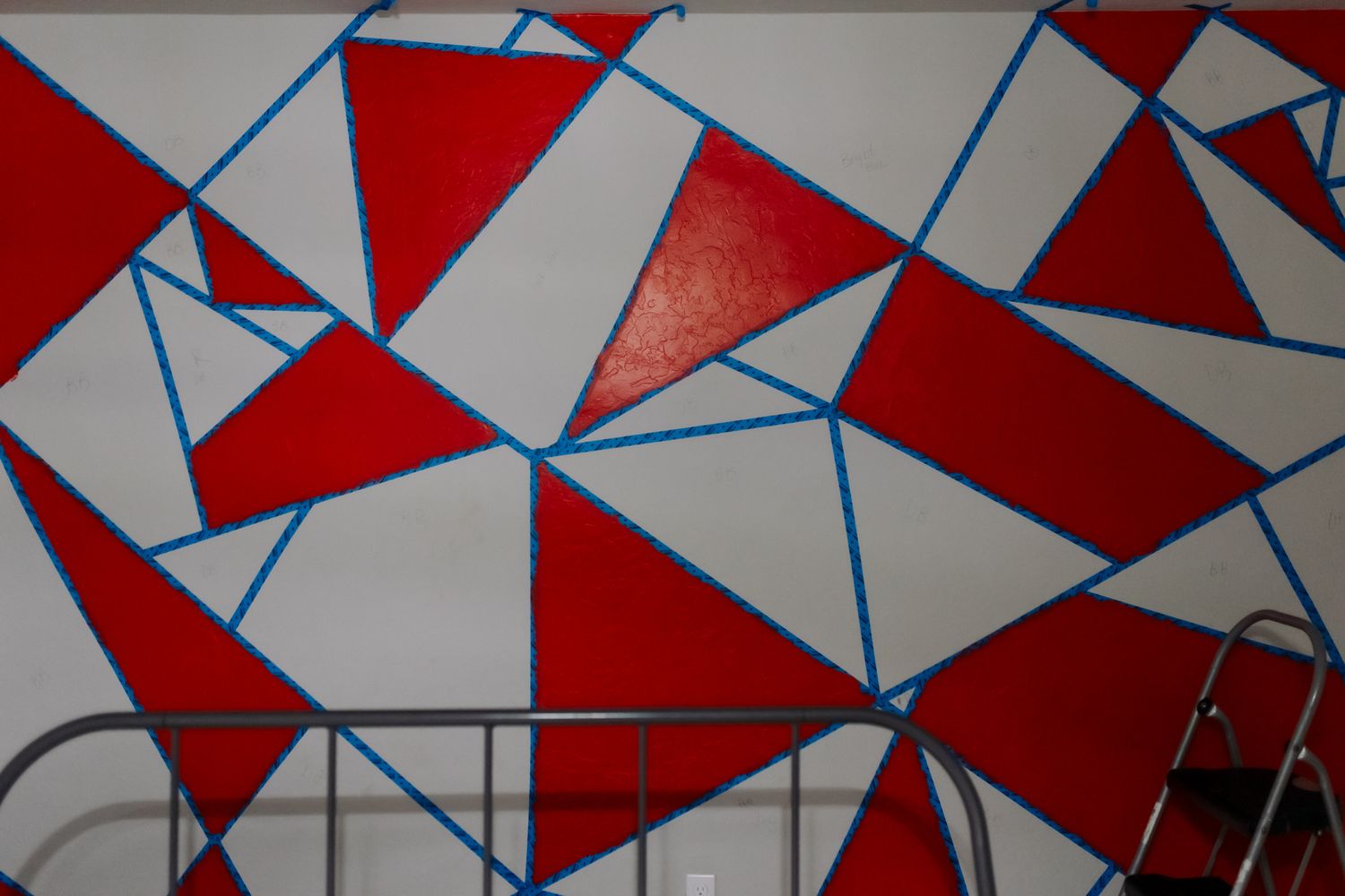 Abstract geometric pattern with red triangles and blue lines forming a modern mosaic design on white background.