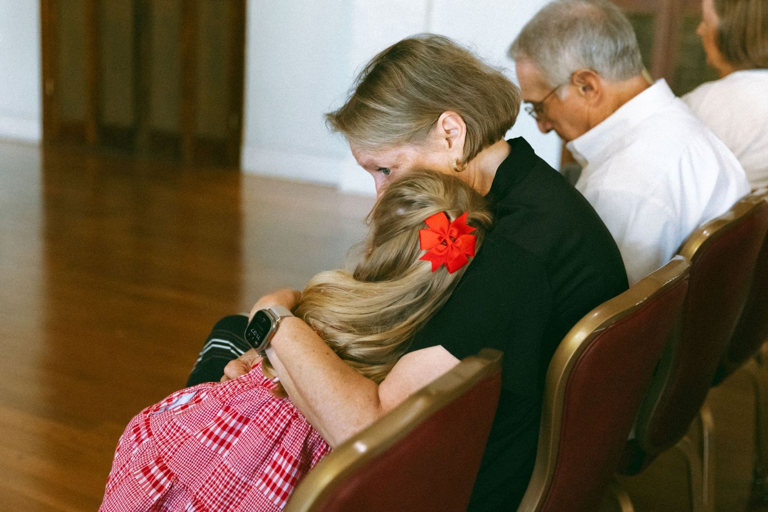 Woman and child sharing a tender embrace while seated in wooden chairs during a family gathering.