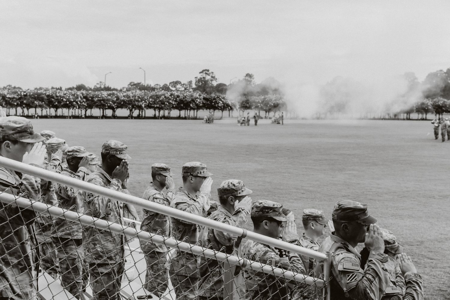 Row of military personnel standing at attention during a formal ceremony on a grassy field.