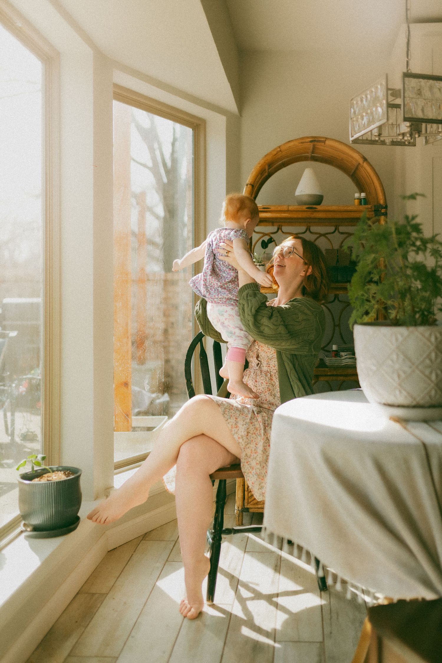 Sunlit room with wooden floors and plants where a child plays near a window on a bright morning.