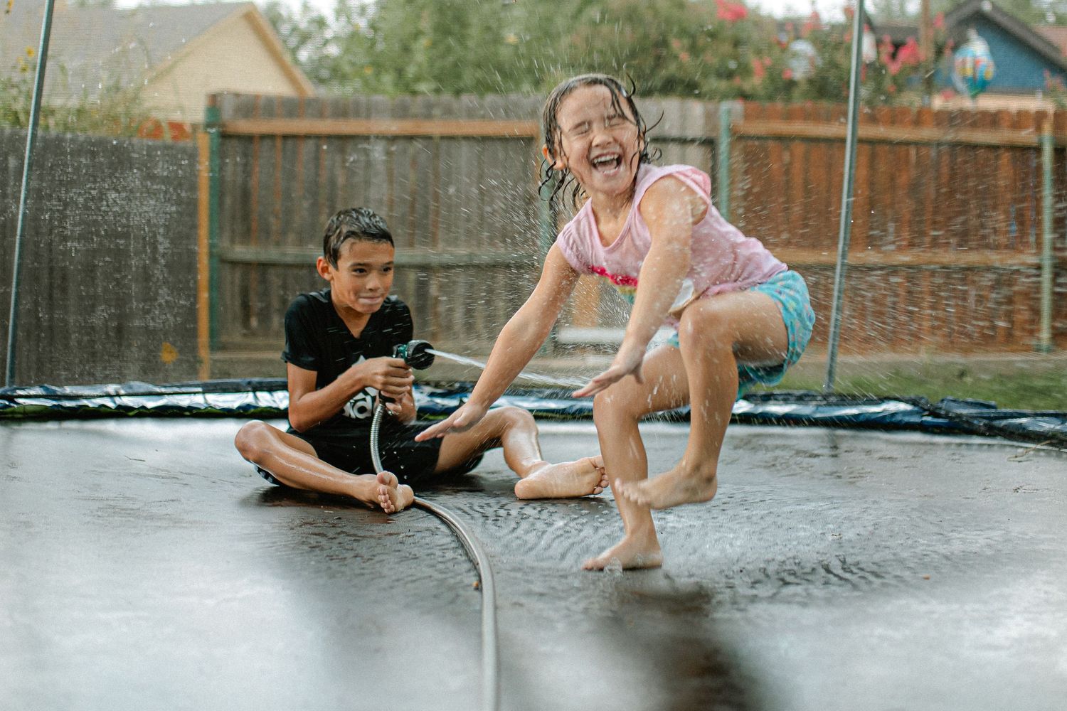 People lounging and playing on a wet trampoline surface in summer fun together. In-Home Photography Liz Perez