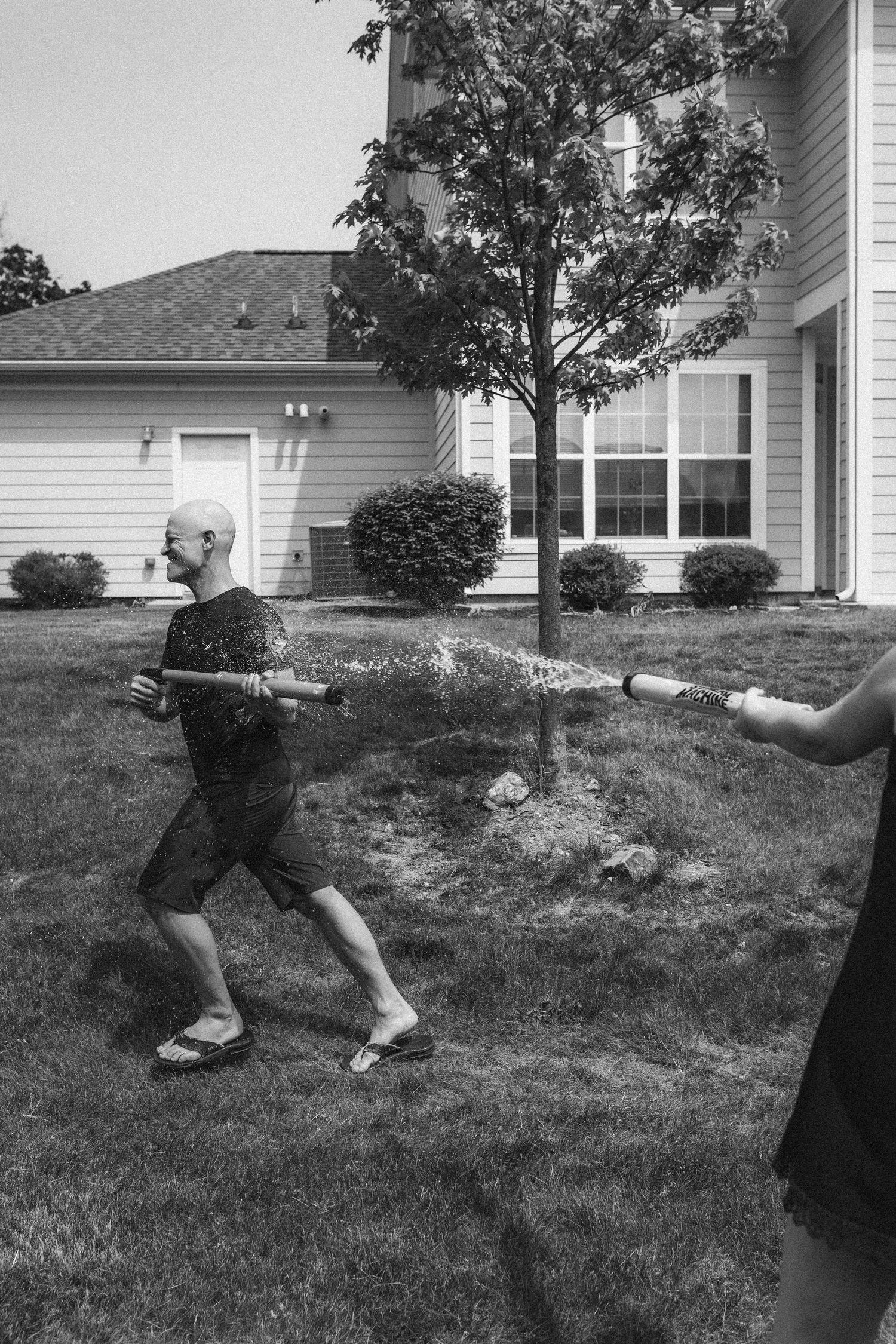 Black and white image of people engaged in a water gun battle outdoors.