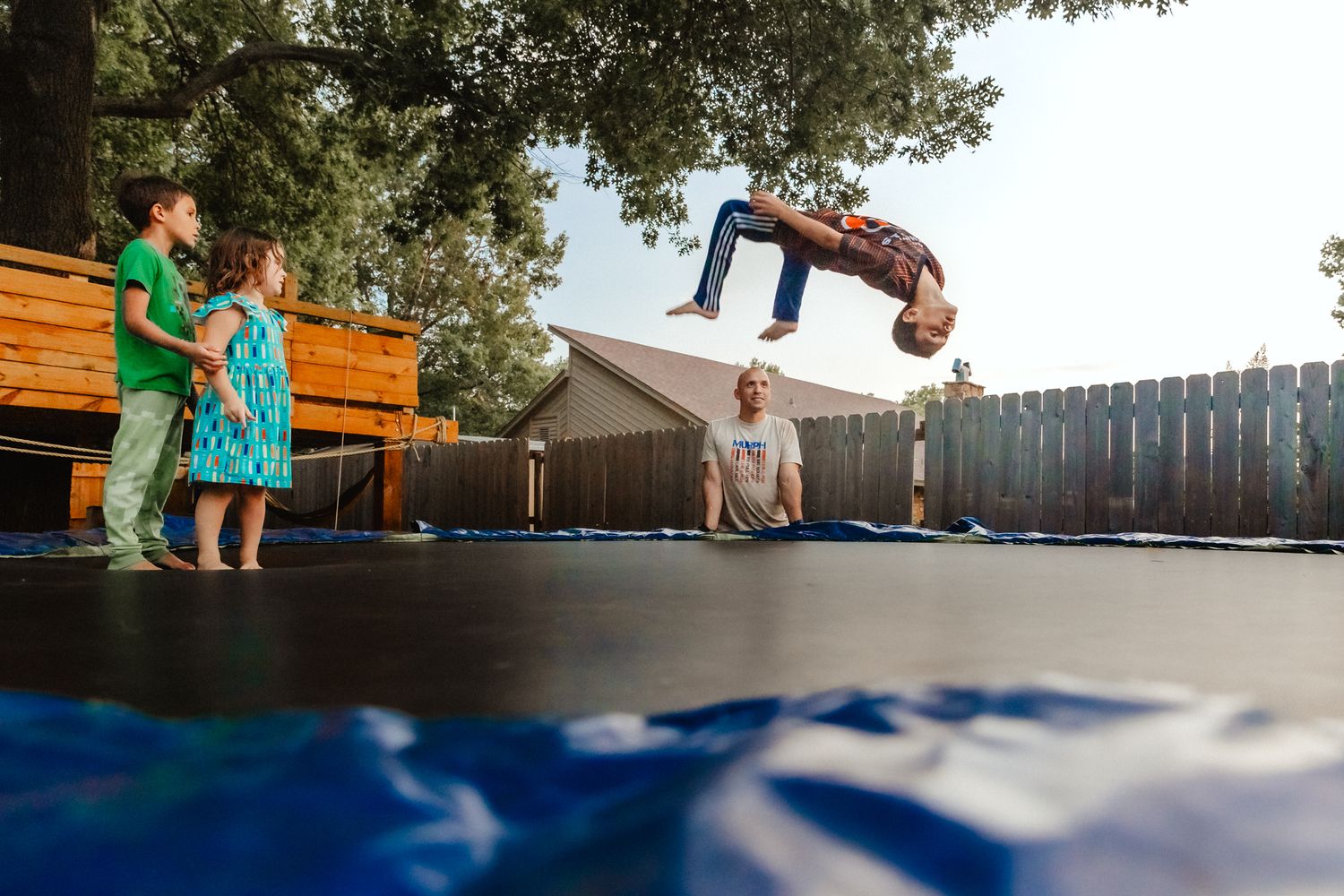 People gathering on a wooden deck or outdoor patio space under trees.