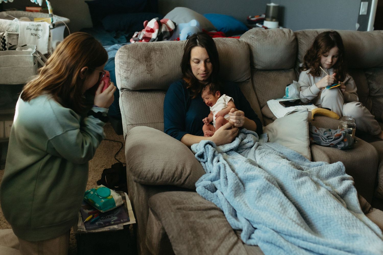 Cozy living room scene with someone relaxing on a grey couch under soft lighting.