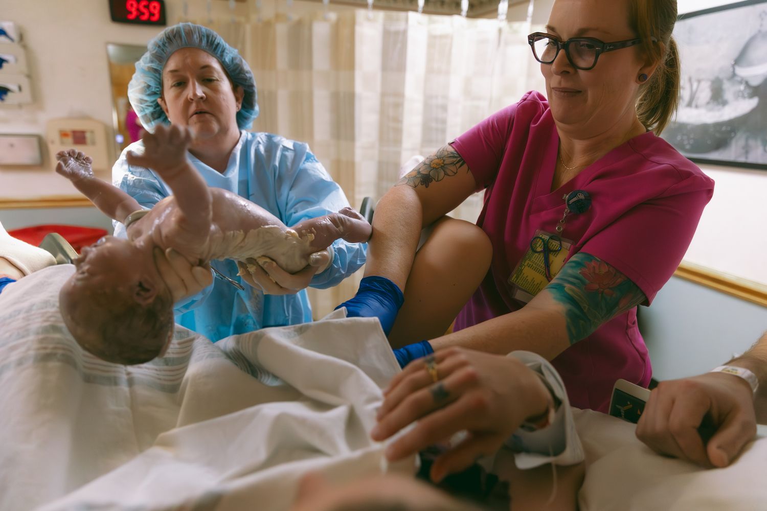 Healthcare workers in blue and pink scrubs assist patients with medical care in a clinical setting.