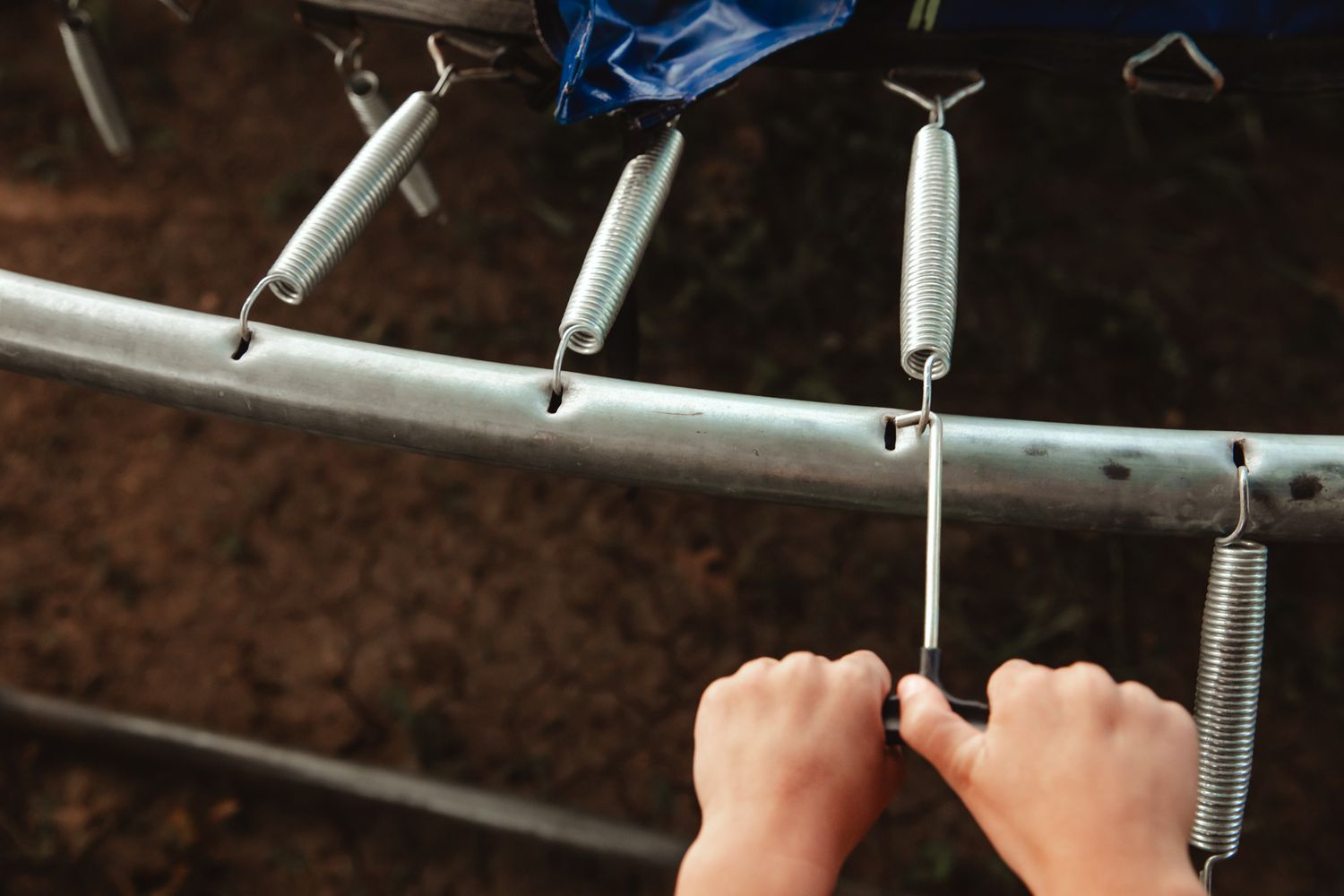 Close-up of hands gripping a metal pull-up bar against a dark background.