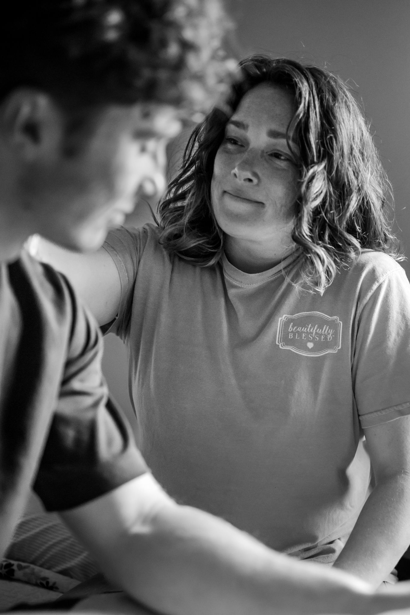 Black and white portrait in soft in home window light showing intimate emotional moment.