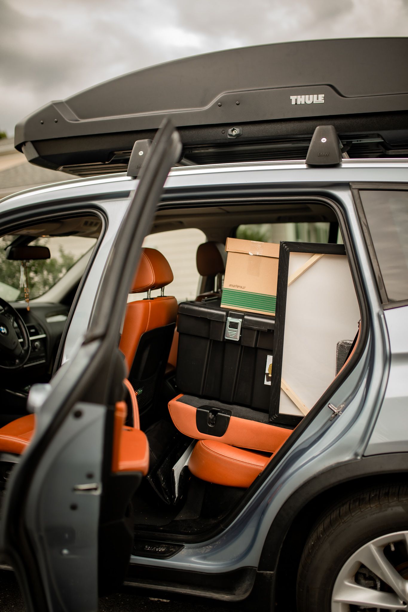 Interior view of an SUV showing orange leather seats and a Thule roof cargo box visible through sunroof. In-Home Photography Liz Perez