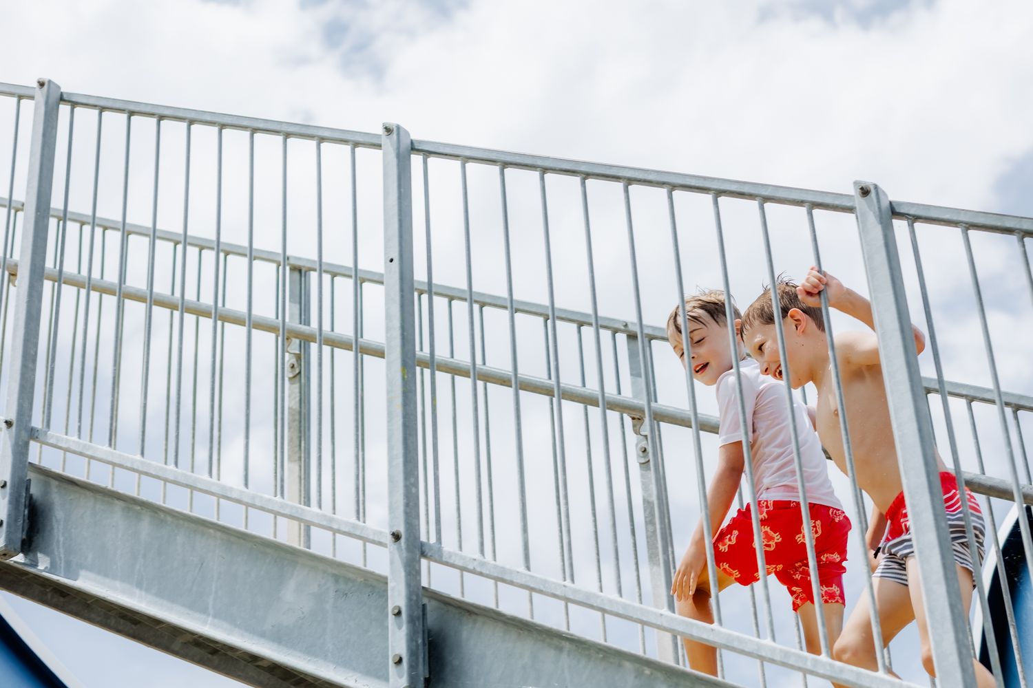 White railing bridge stretches across a body of water on a cloudy day.
