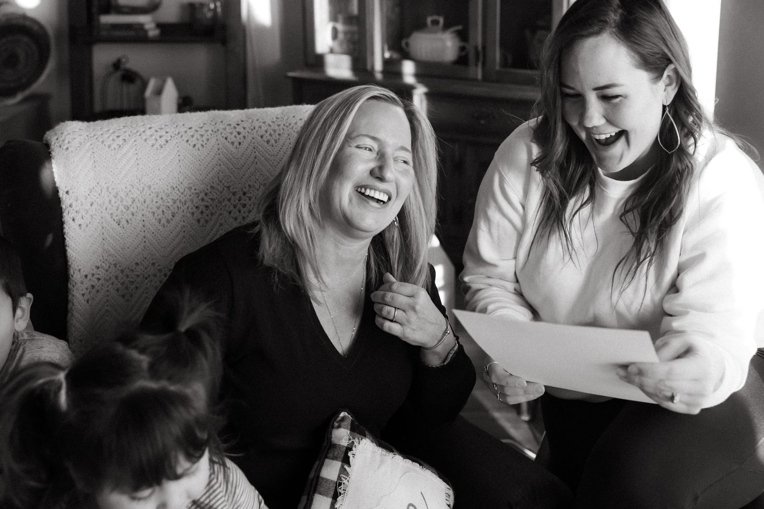 Black and white photo of people sharing a joyful moment while reading together.