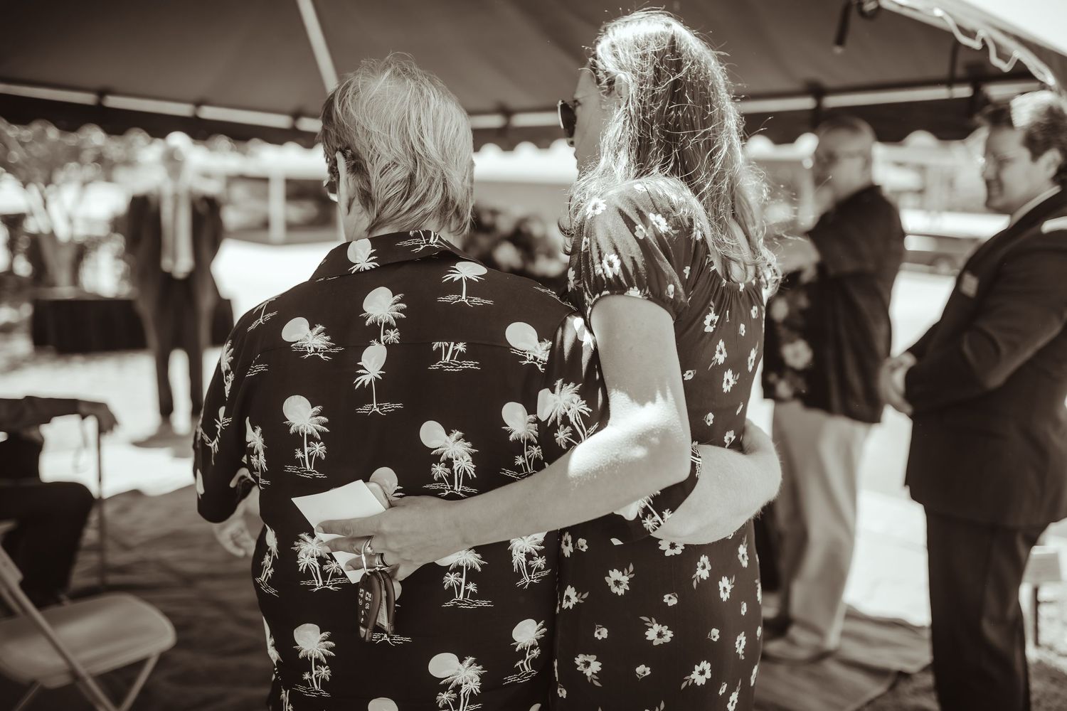 Crowd mingling under white and green canopy tents at an outdoor event.
