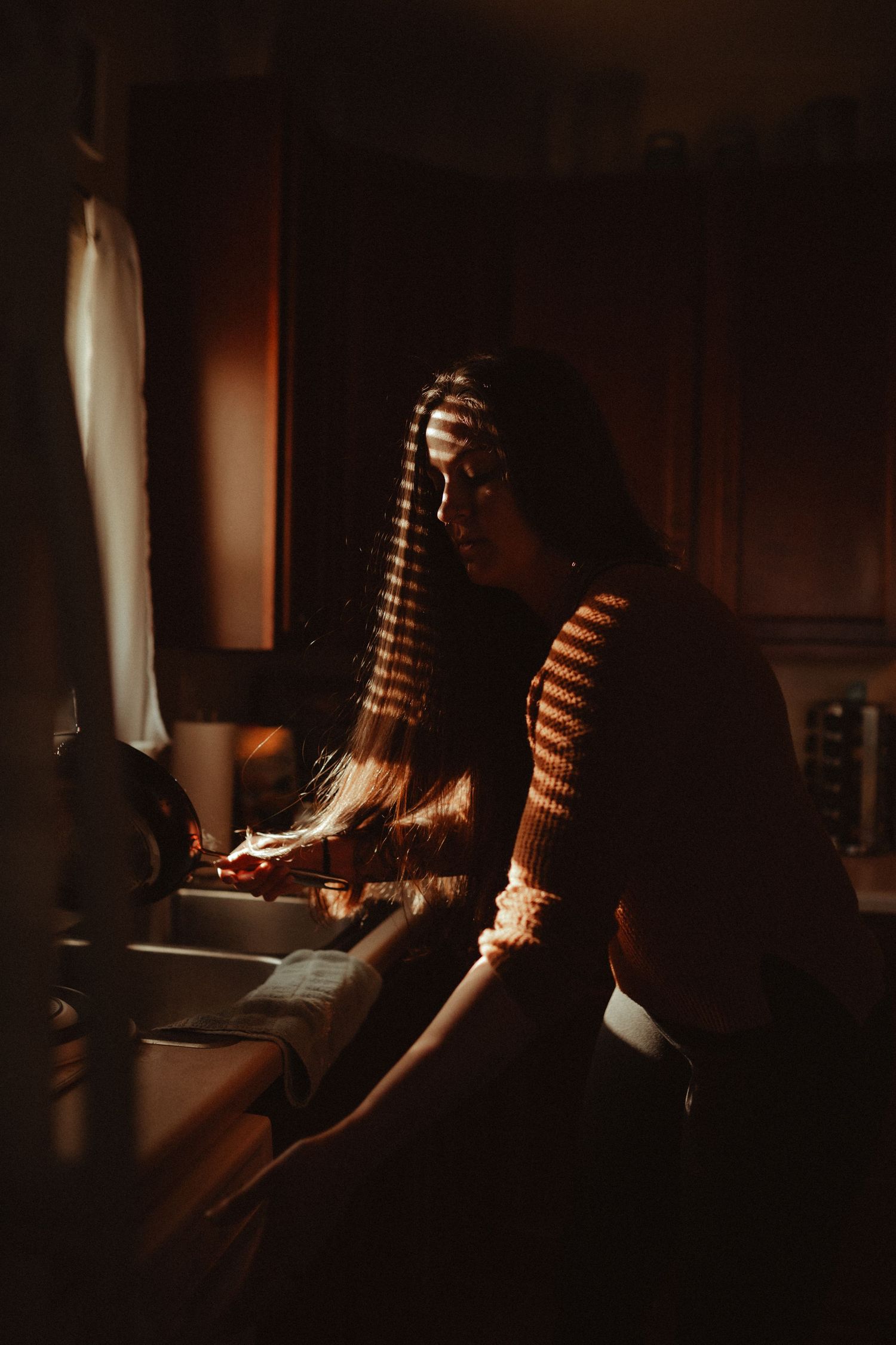 Person in striped sweater sitting at desk in moody lighting.