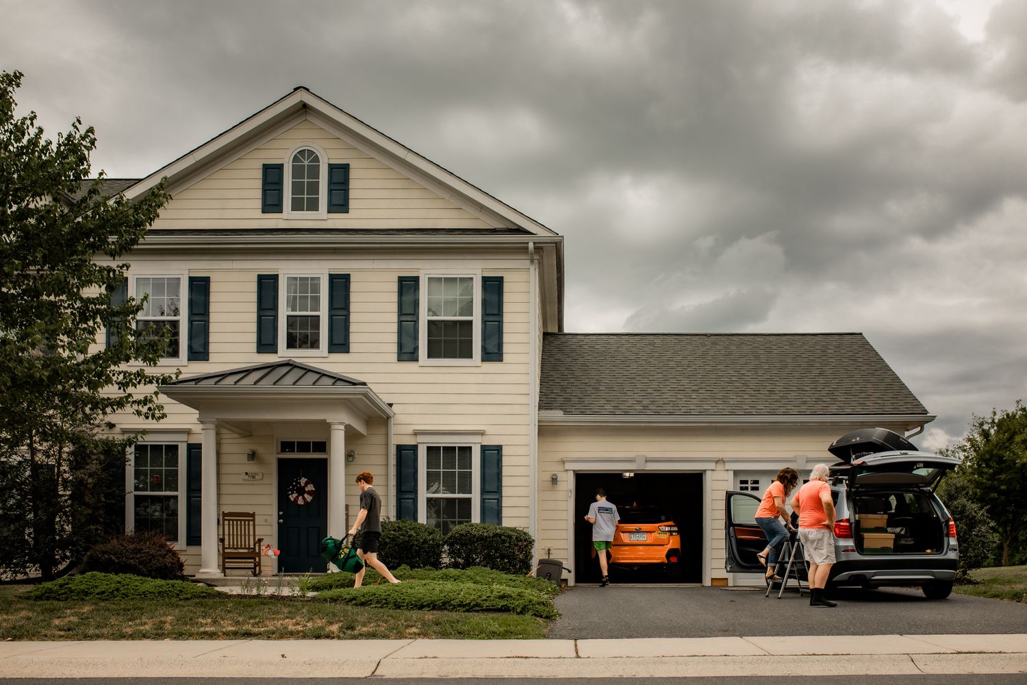 Exterior view of a white two-story suburban house with attached garage under cloudy skies. In-Home Photography Liz Perez