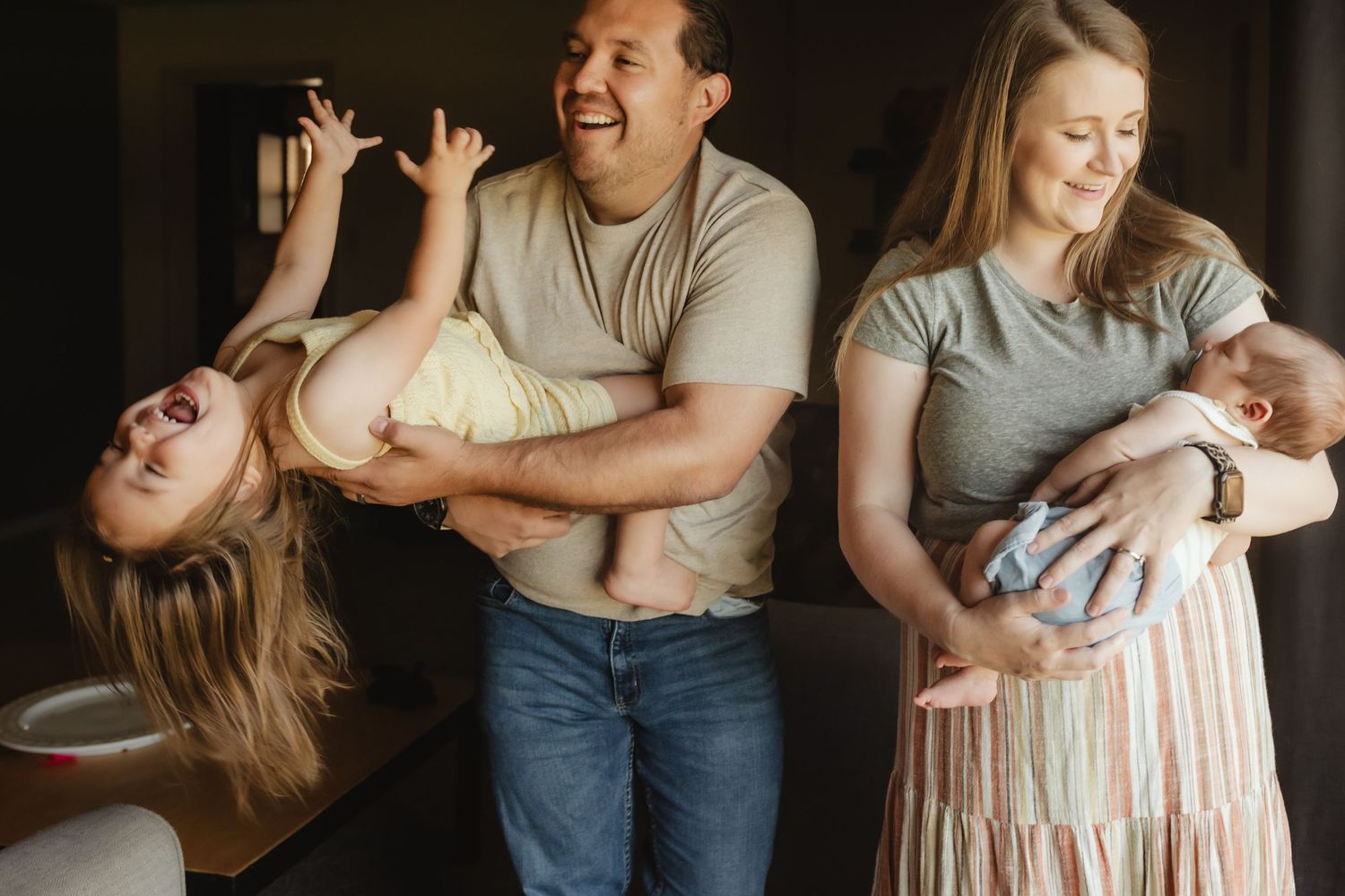 A series of intimate lifestyle photos showing tender moments between parents and their baby in a dimly lit setting.