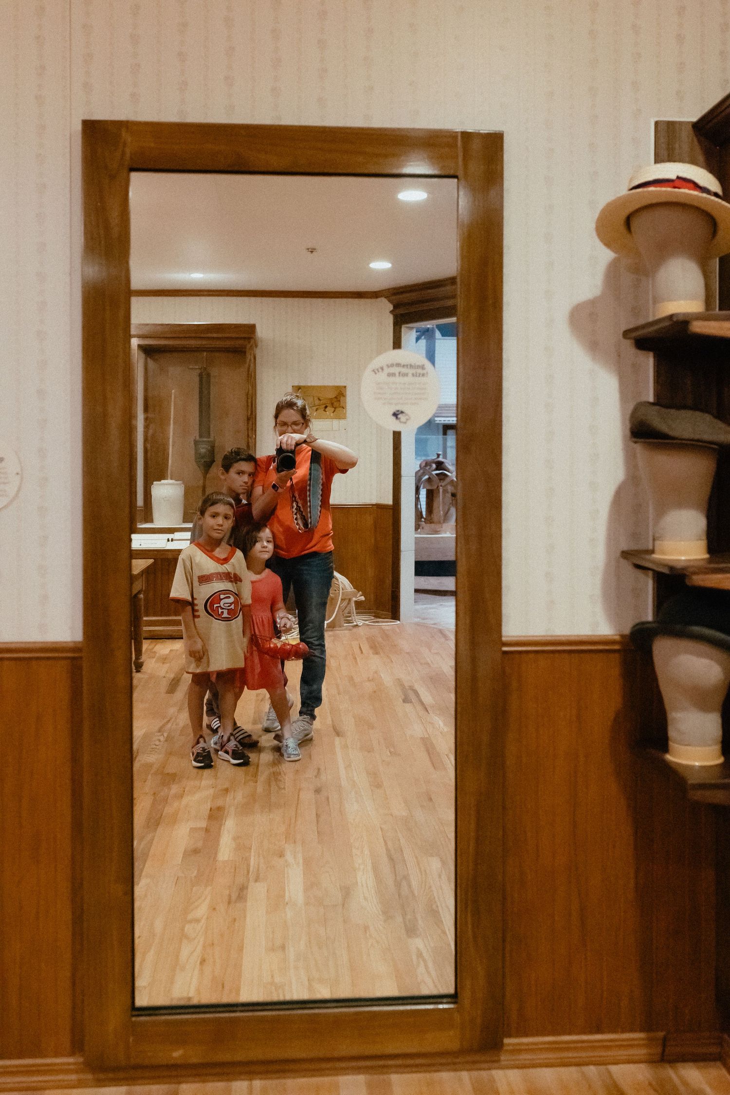 Fun house museum exhibit with distorted mirror reflections on wooden floors showing visitors in amusing poses.
