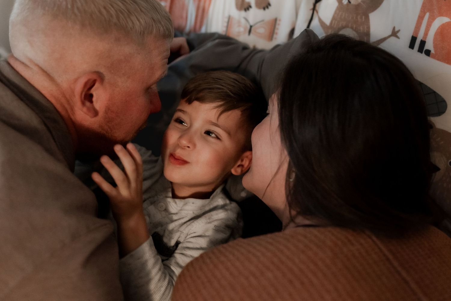 Intimate family moment captured during bedtime routine in dim lighting.