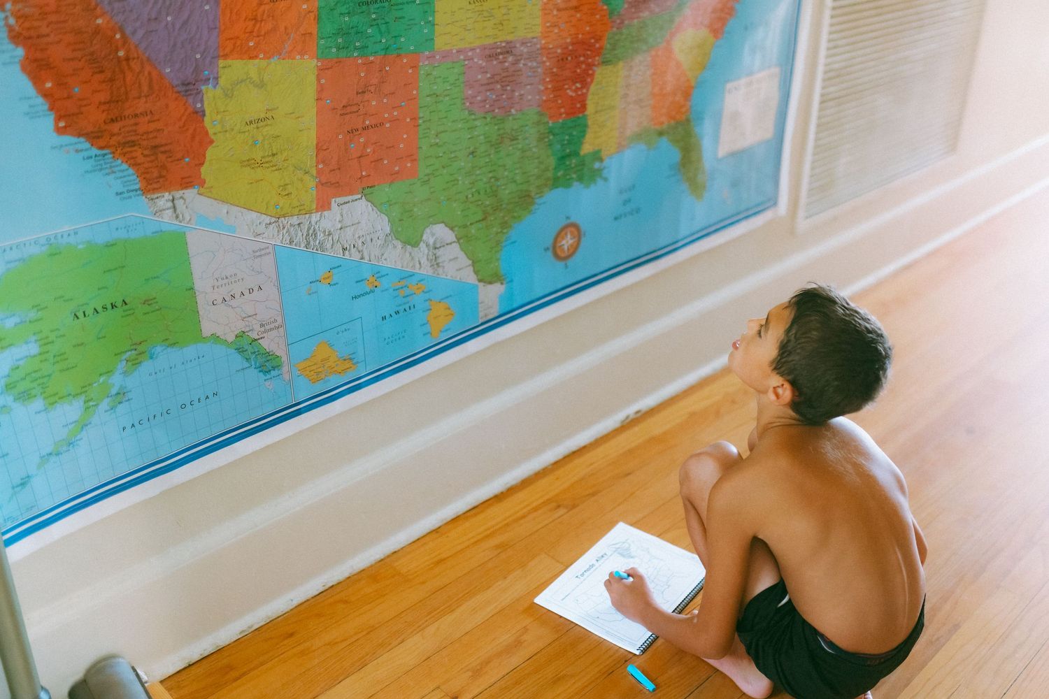 Colorful world map wall hanging being used for education and learning in a bright room setting.