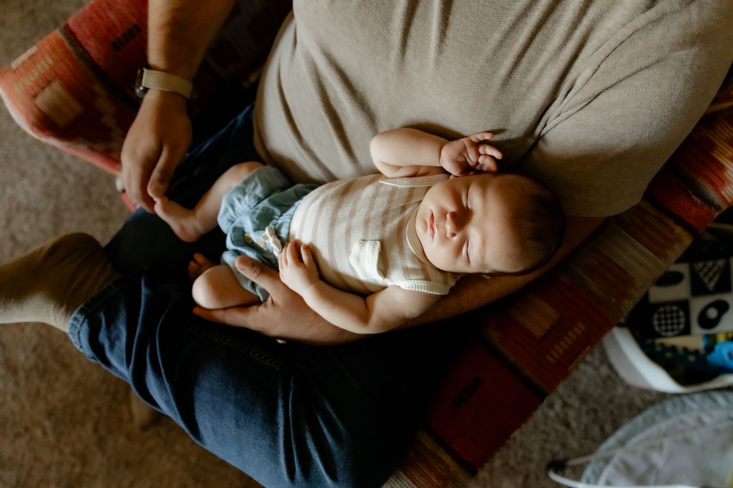 Newborn baby in white onesie lying on dark blanket during peaceful sleep.